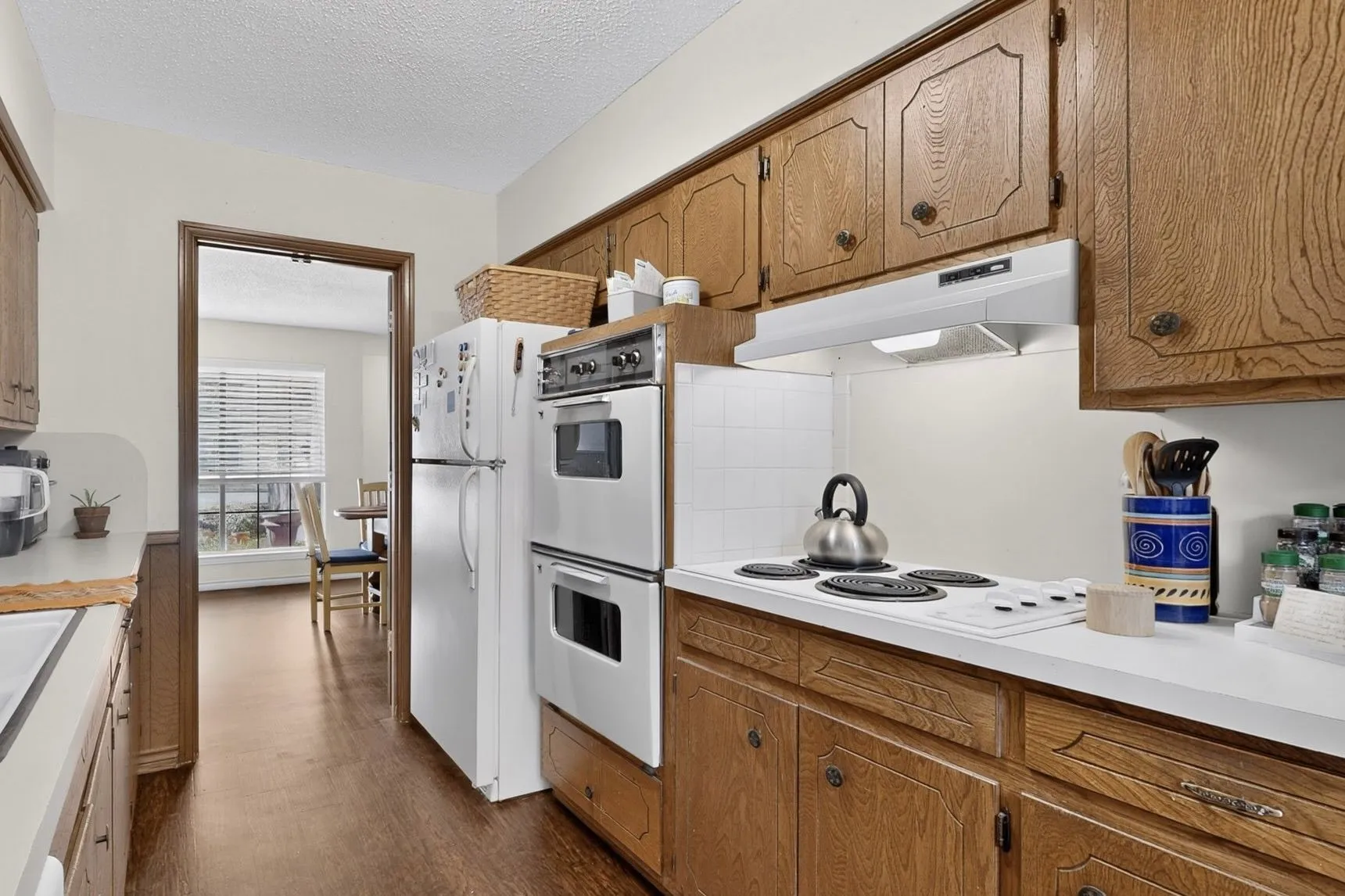 Kitchen featuring wood-finish cabinetry, white countertops, a built-in double oven, and a white refrigerator