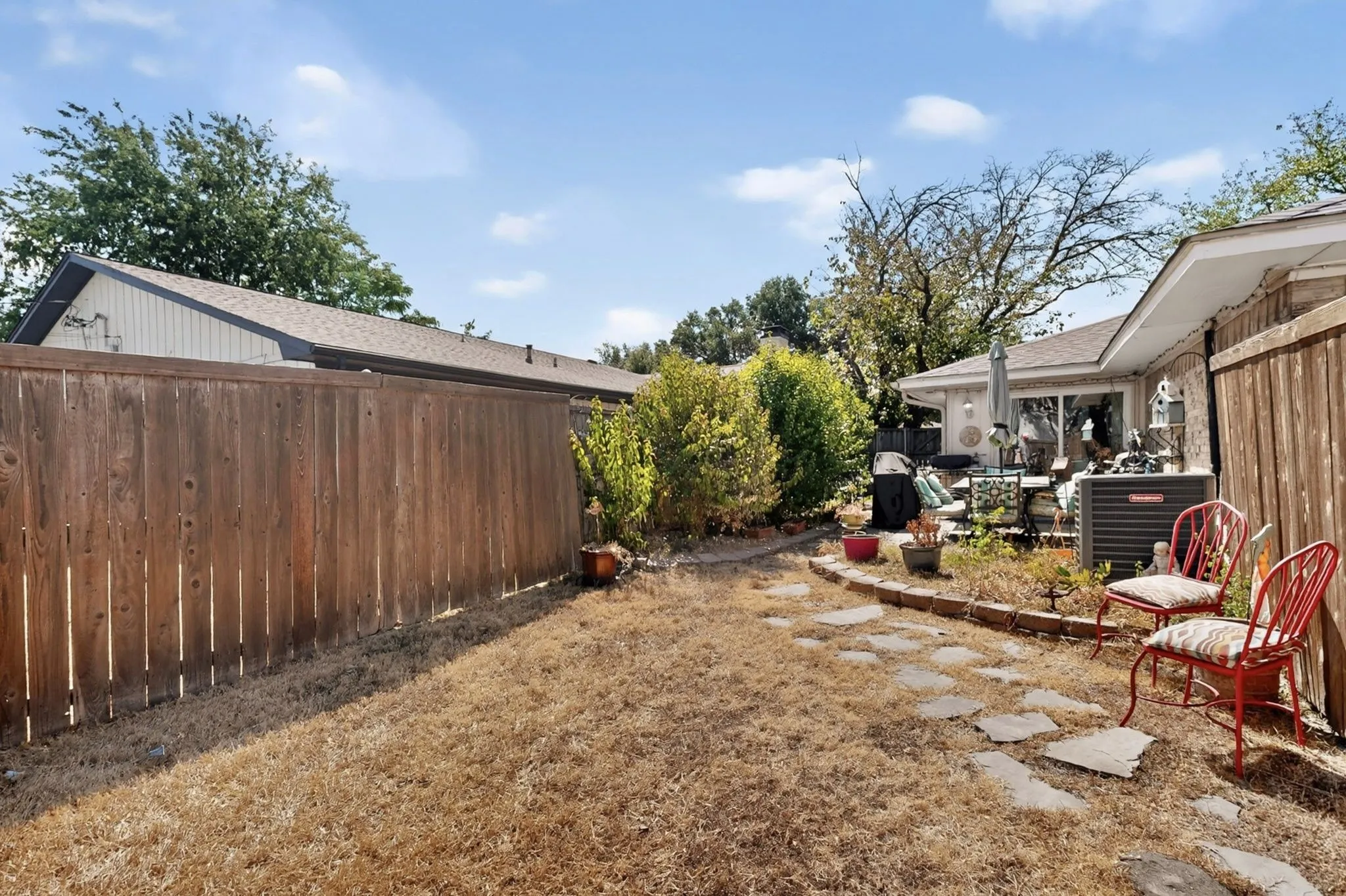 Patio area with a sliding glass door, stone paver pathway, and mature landscaping