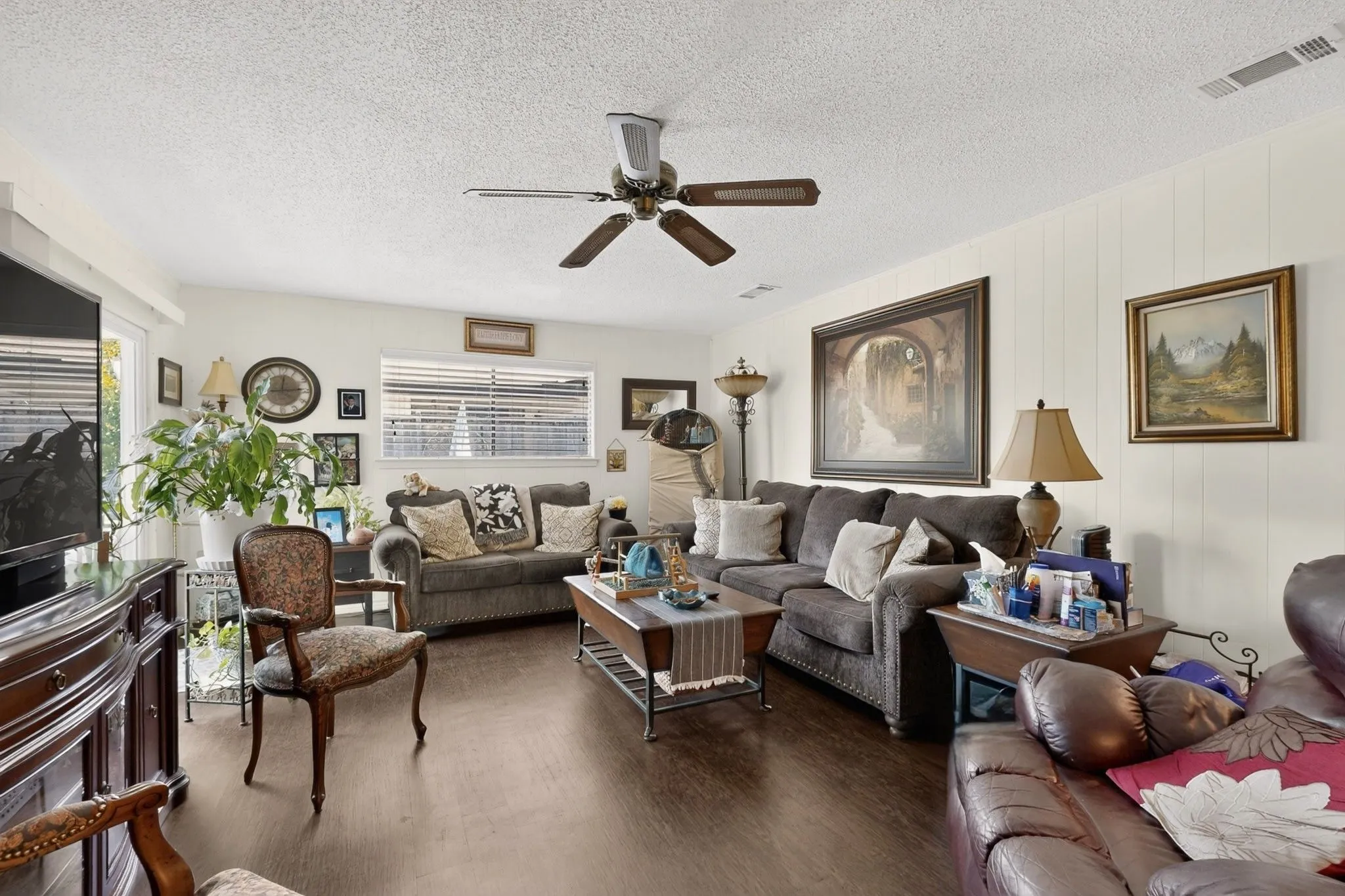 Wood-finish flooring, ceiling fan, white paneled wall accent, window with blinds
