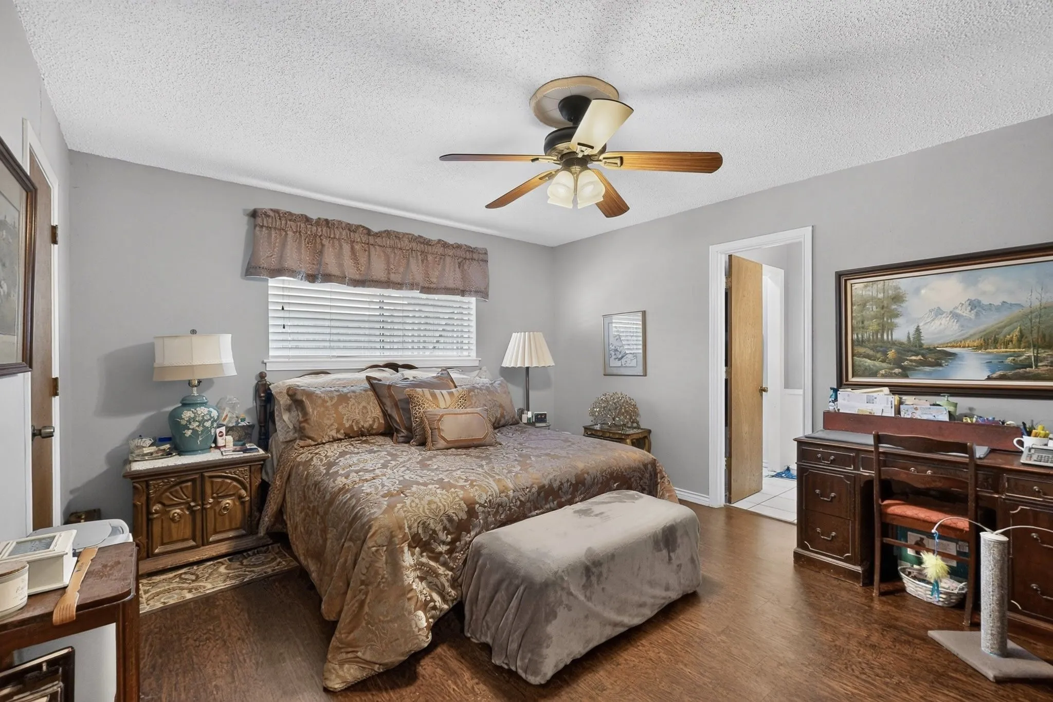 Wood-finish flooring, ceiling fan with integrated lighting, window with blinds, and light gray wall paint