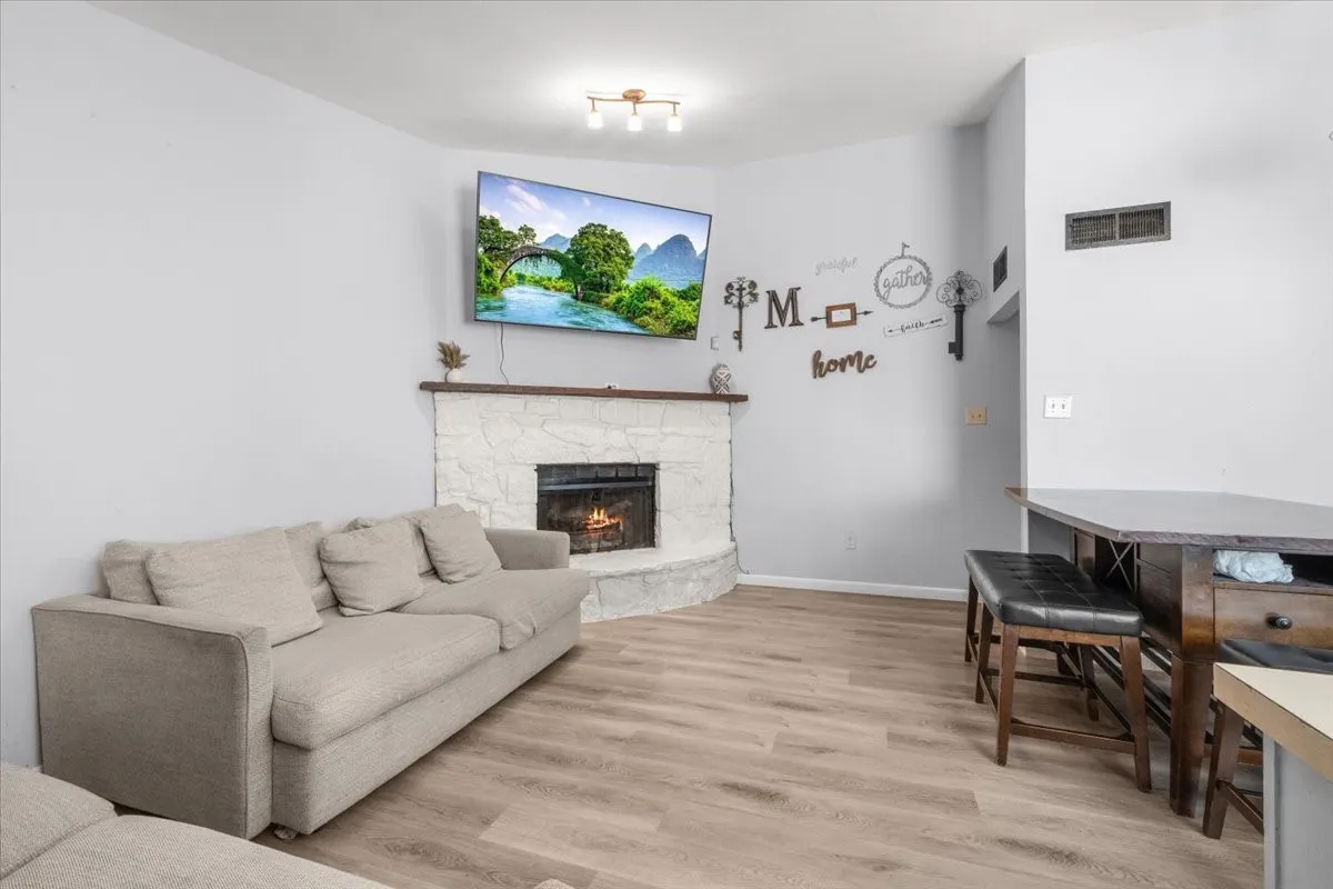 Corner fireplace with a wood mantel, light wood-finish flooring, and light gray walls