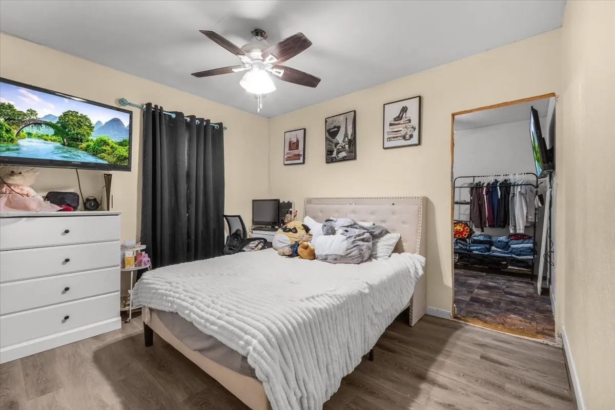 Light wood-finish flooring, ceiling fan with integrated lighting, and a soft neutral wall color