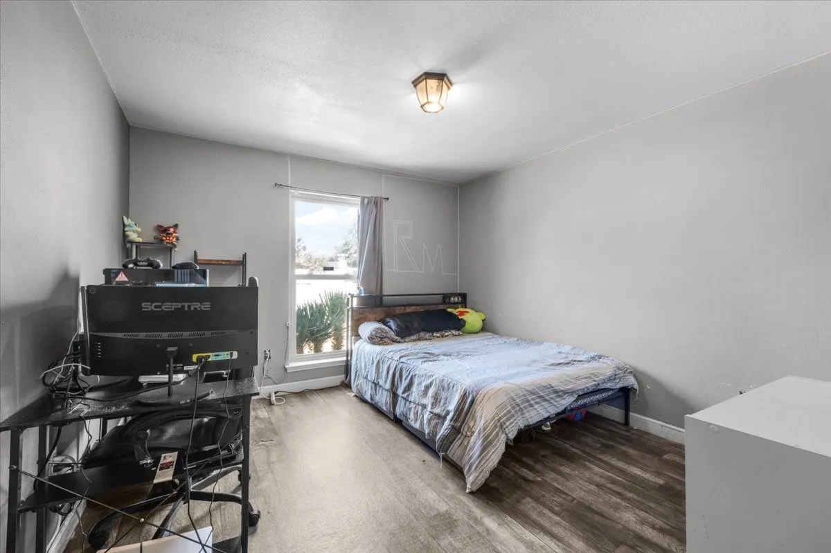 Interior room featuring wood-finish flooring, a single window, and a ceiling-mounted light fixture