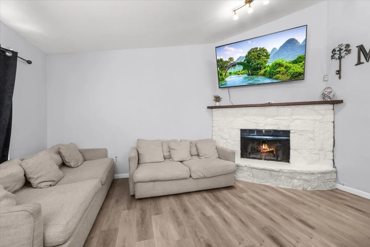 Corner fireplace with a white stone finish and a wood mantel