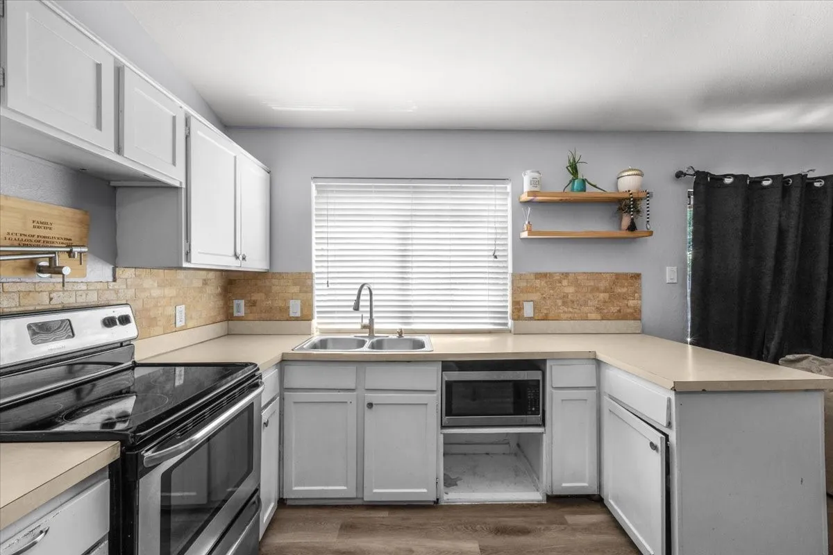U-shaped kitchen featuring white cabinetry, light-toned countertops, and a tiled backsplash