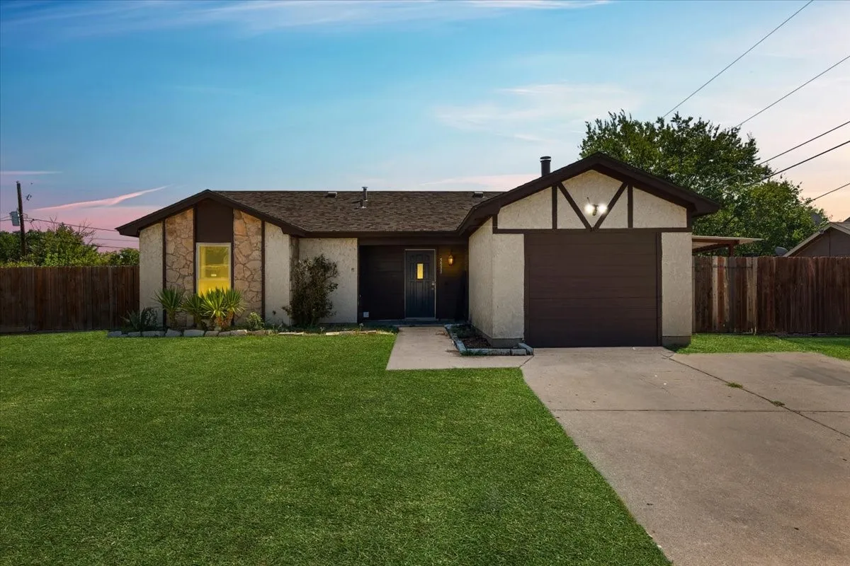 Stucco exterior featuring stone accents, a dark brown garage door, and a concrete driveway