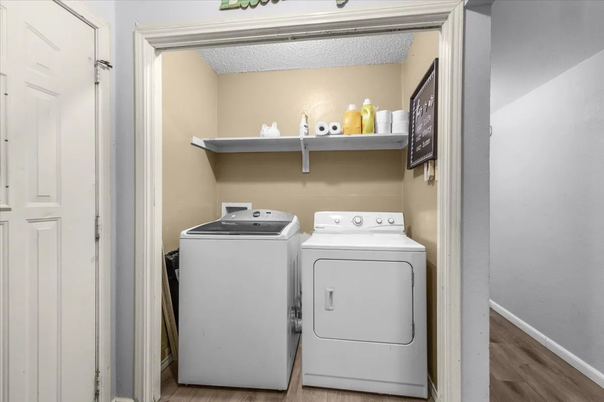 Dedicated laundry area featuring a built-in shelf and wood-finish flooring