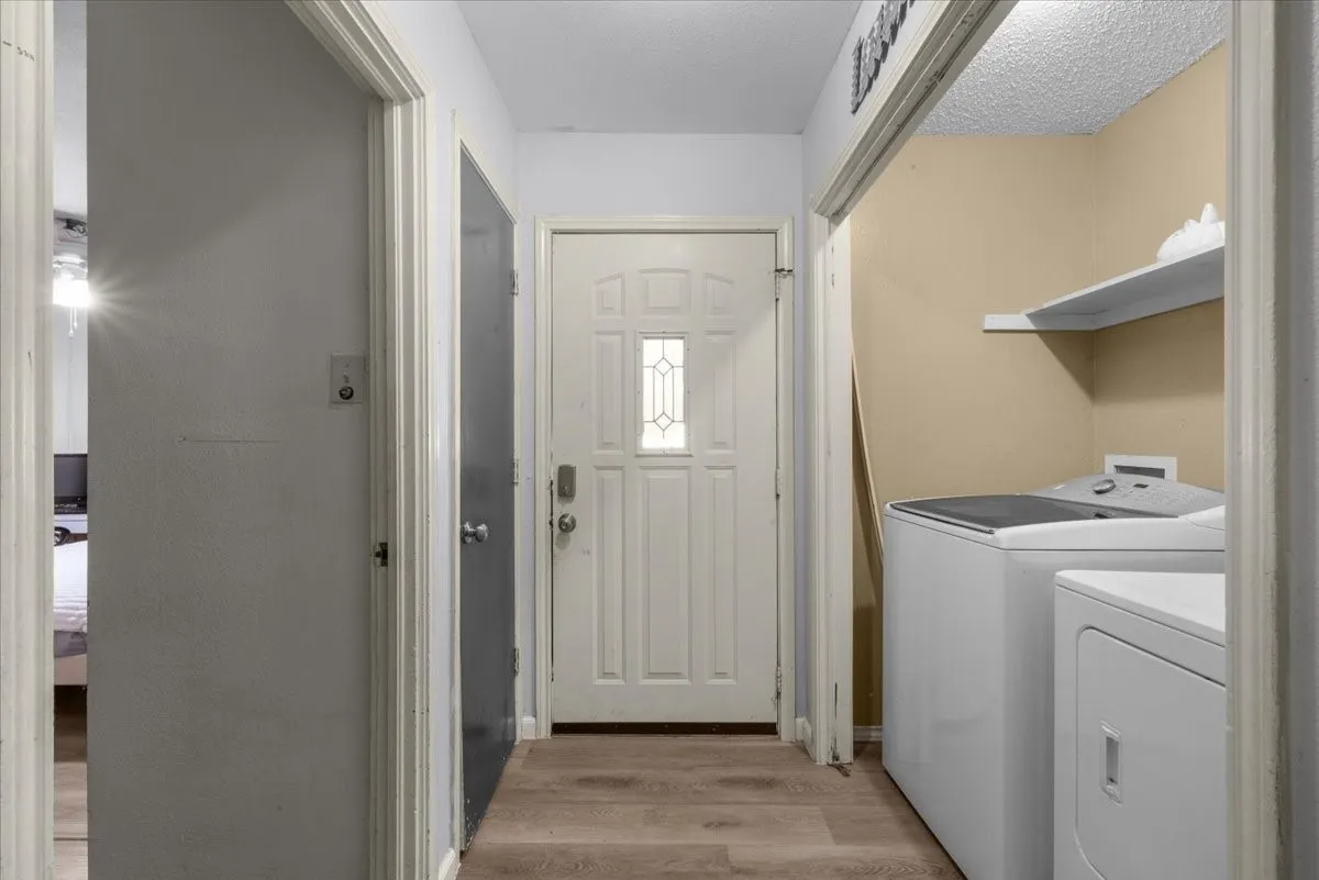 Wood-finish flooring throughout, a paneled entry door with decorative glass, and a dedicated laundry area with shelving