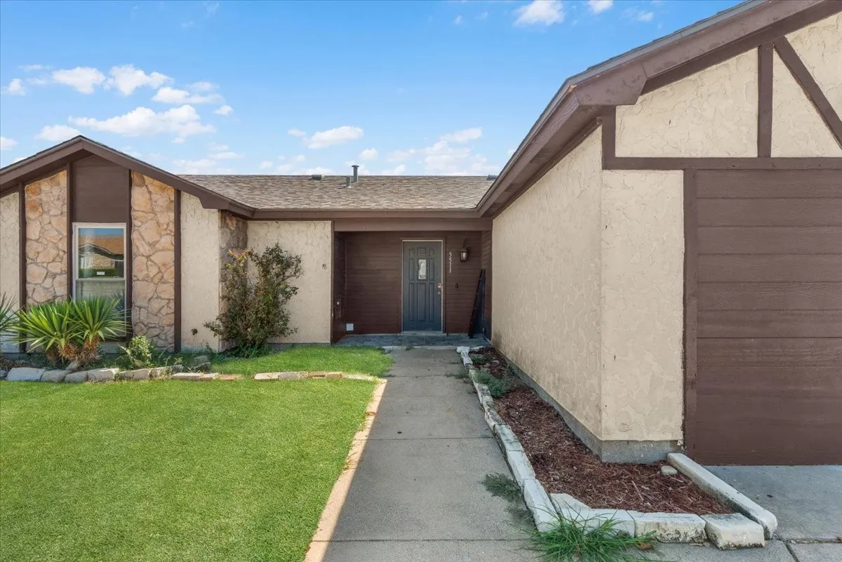 Exterior featuring stone veneer accents, stucco siding, a brown garage door, and a concrete pathway