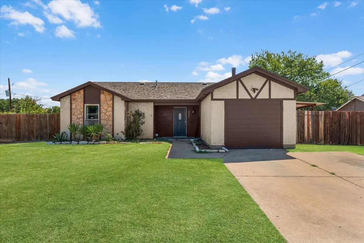 Single-story residence featuring a shingled roof and an attached garage with a dark wood-finish door