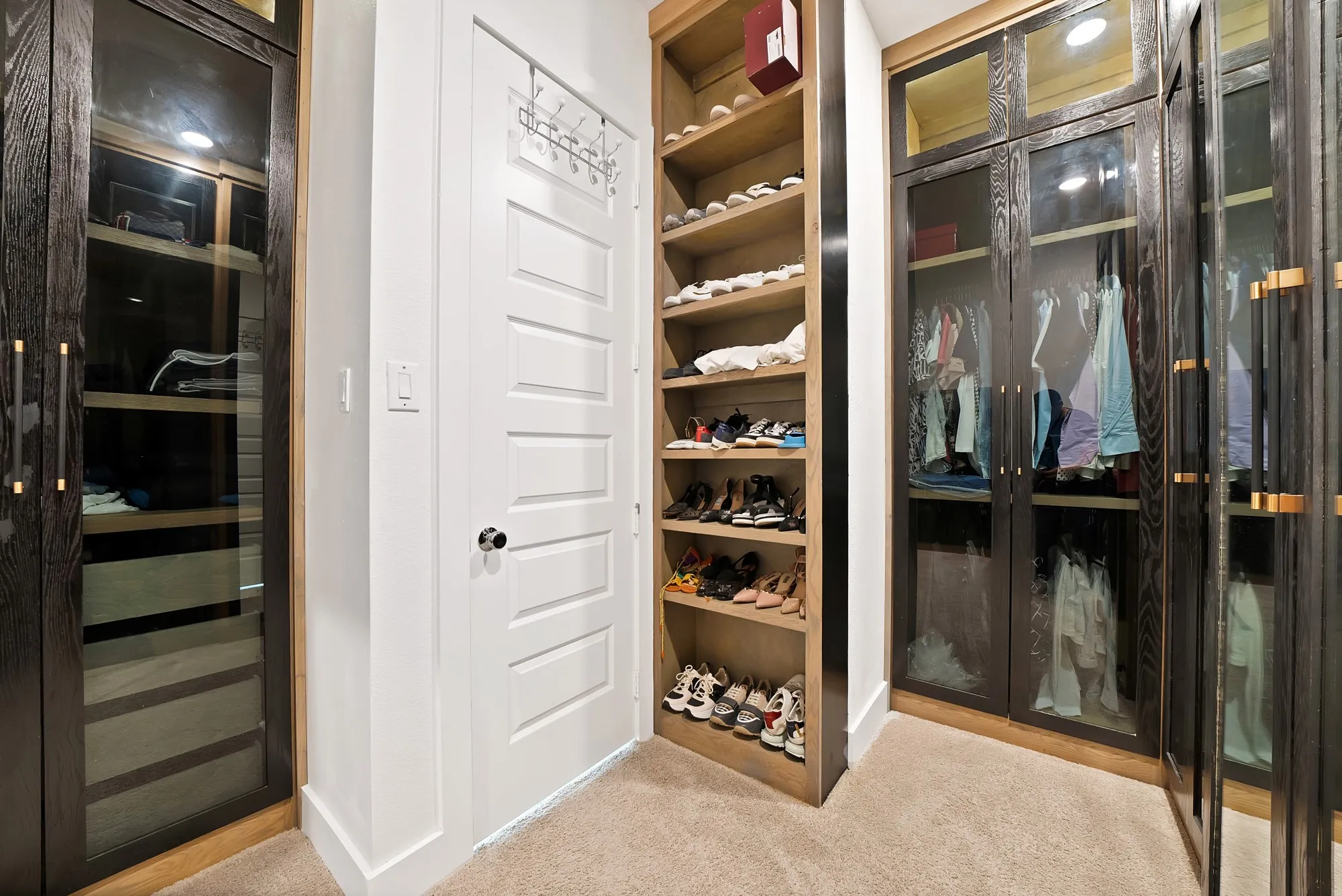 Built-in custom cabinetry with glass-front doors, open shelving storage, and light-toned carpet​​‌​​​​‌​​‌‌​‌‌​​​‌‌​‌​‌​‌​​​‌​​ flooring