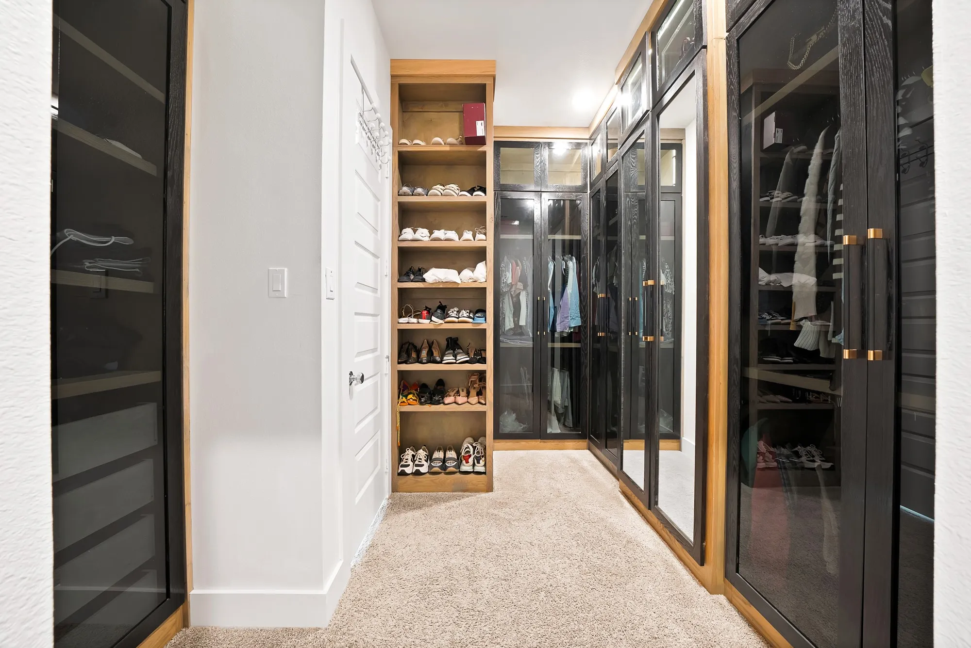 Custom closet system featuring glass-front doors, integrated shelving, and wood-finish accents