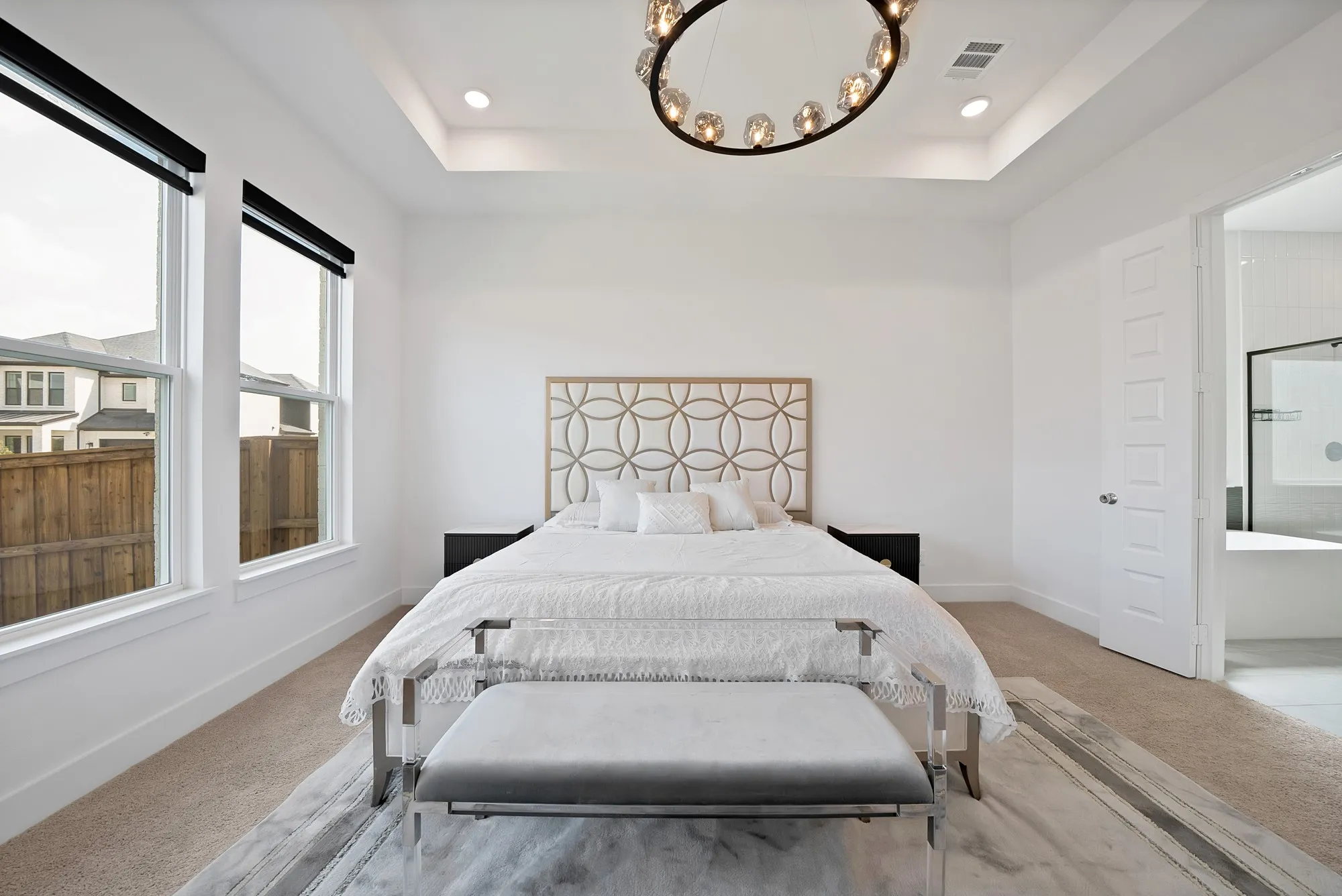 Tray ceiling with recessed lighting, two windows, textured wall paneling, circular chandelier, and an open doorway