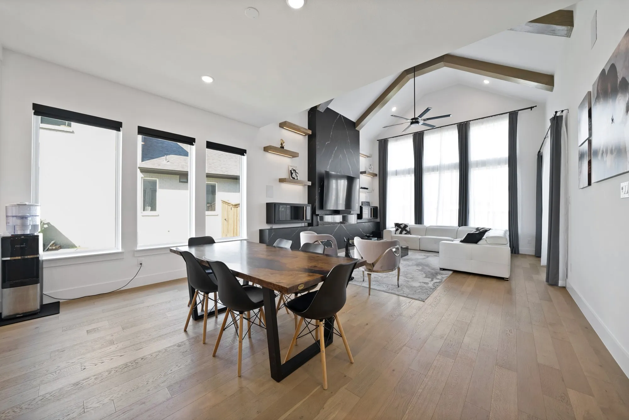 Vaulted ceiling with exposed wood beams, wood-finish flooring, and a stone-clad fireplace