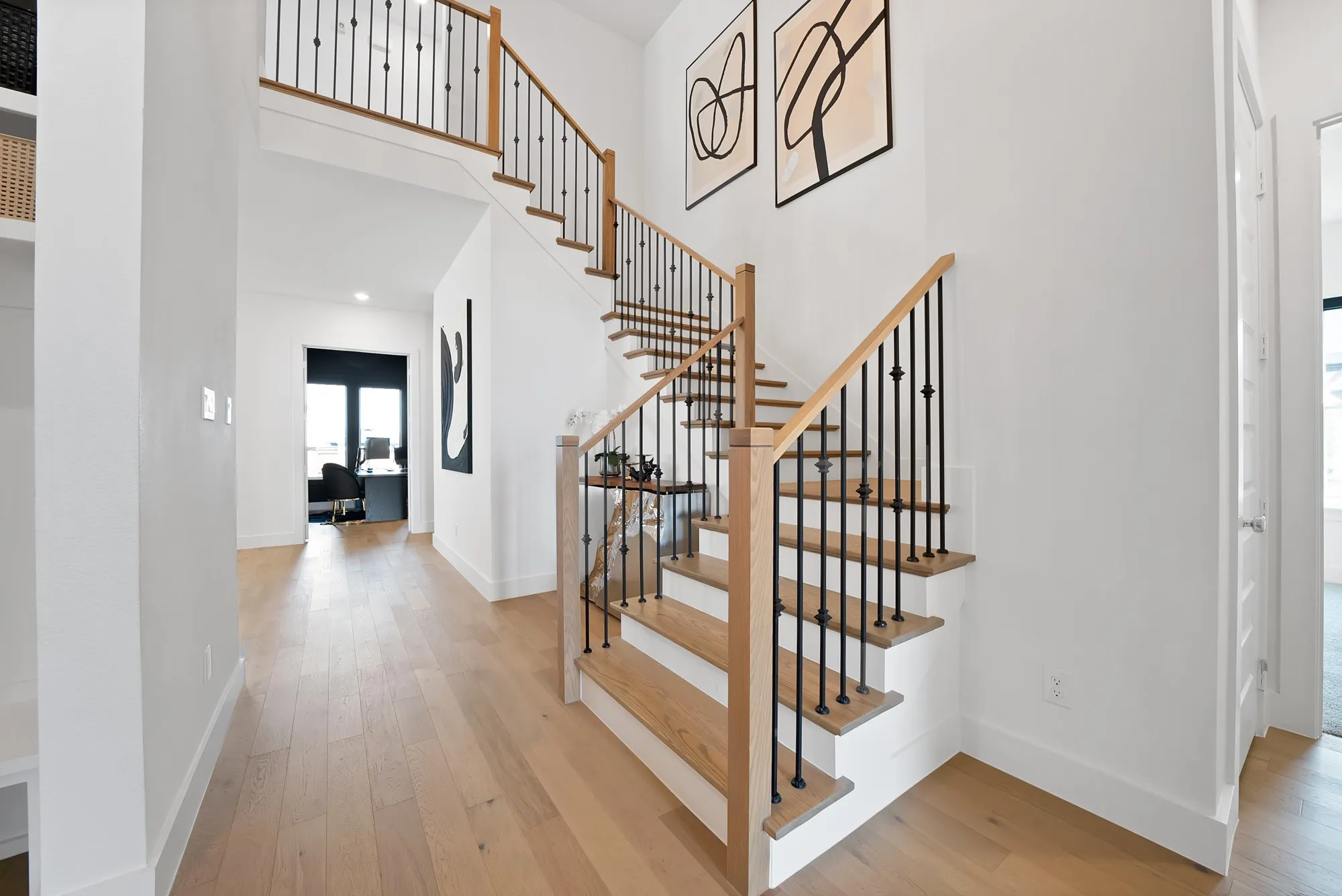 Hardwood flooring throughout, modern staircase with wood-finish handrails and black metal balusters, white painted walls, and recessed lighting
