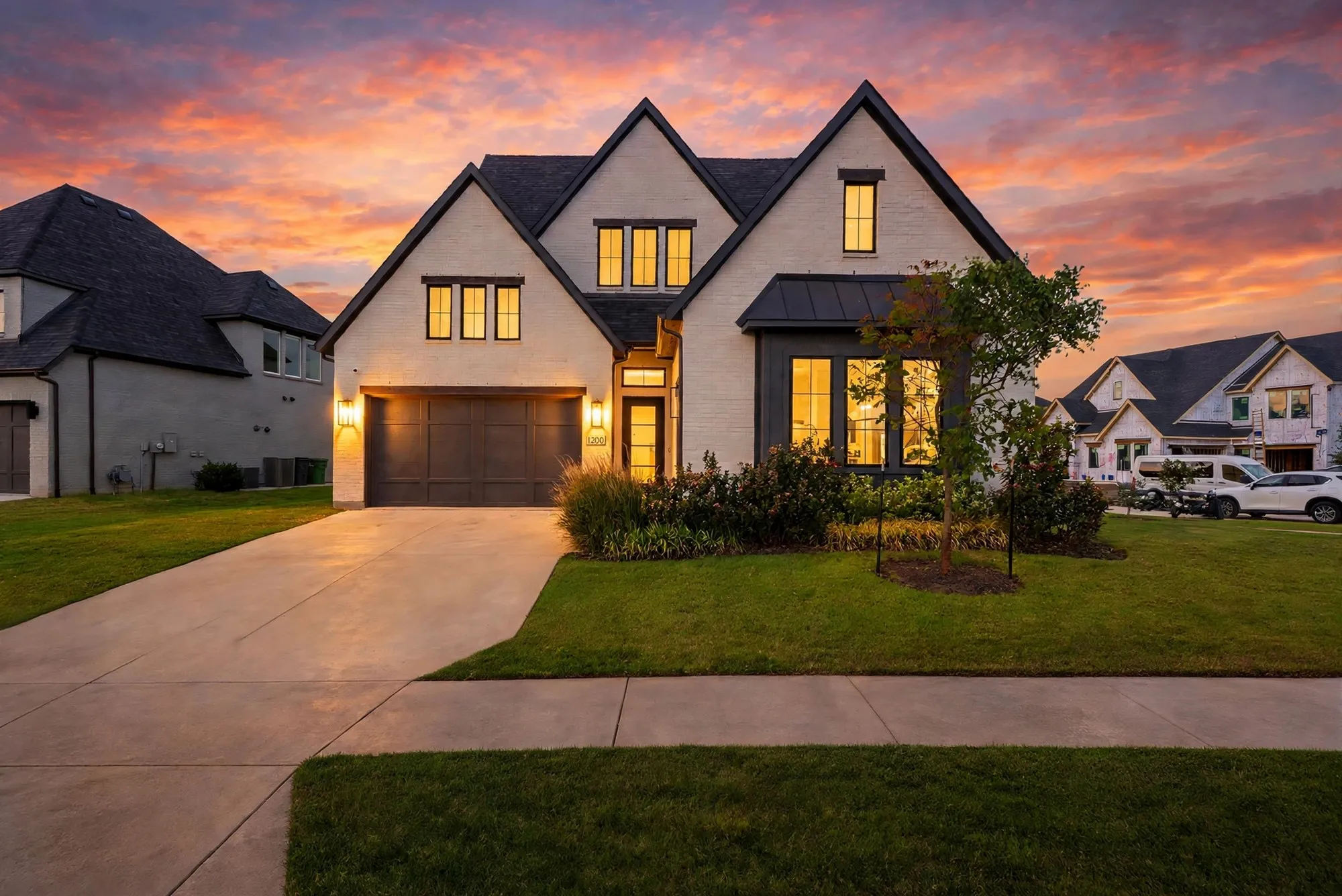 Modern Tudor-inspired exterior with a dark shingle roof and light-colored brick facade