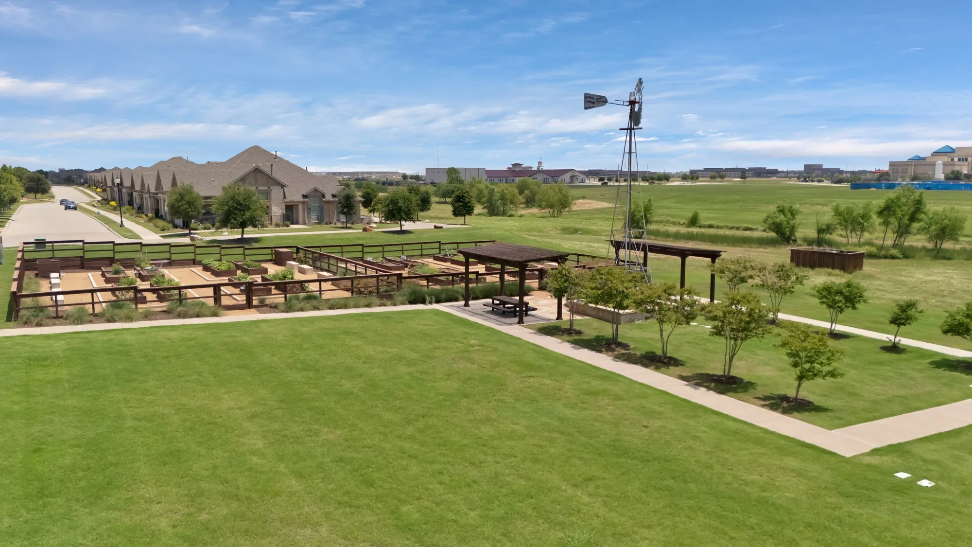 Expansive greenspace with a community garden, pergola-covered seating area, and decorative windmill