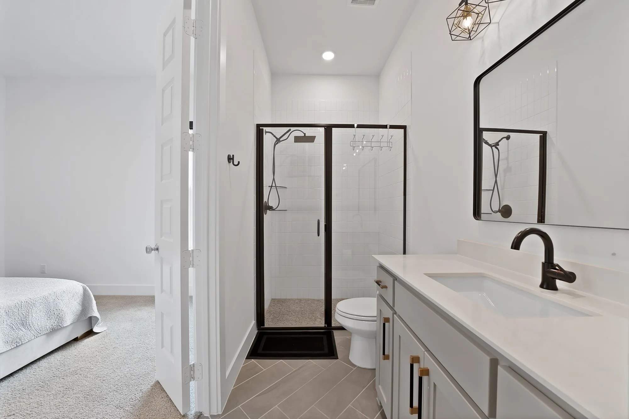 Spacious bathroom featuring a single vanity with an integrated sink, black hardware, a black-framed mirror, and a glass-enclosed shower with a black frame