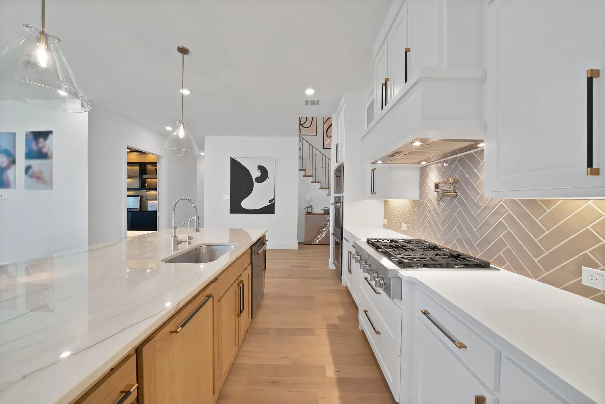 Full kitchen featuring a gas range, herringbone tile backsplash, white shaker cabinetry, stainless steel sink, and wood-finish flooring