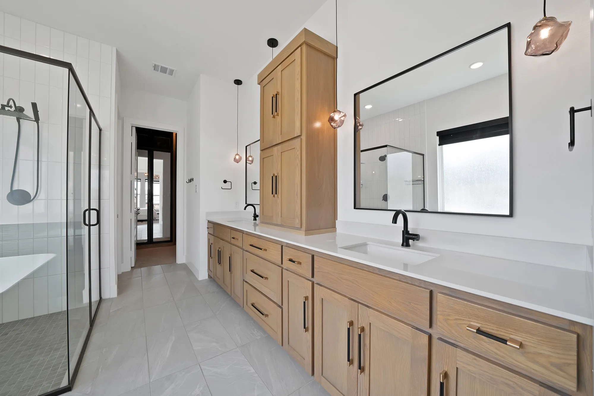 Dual wood-finish vanities with integrated sinks, white countertops, and black fixtures