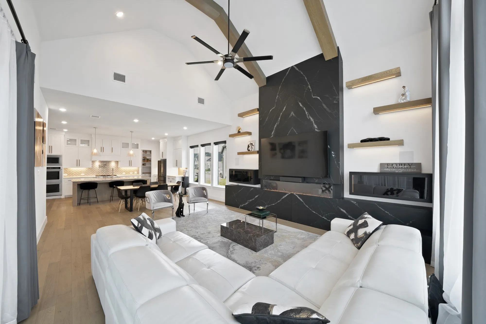 Vaulted ceiling with exposed wood beams, wood-finish flooring, a contemporary fireplace with a dark stone surround, recessed lighting, and a modern ceiling​​‌​​​​‌​​‌‌​‌‌​​​‌‌​‌​‌​‌​​​‌​​ fan