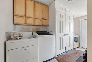 Laundry area featuring wood-finish cabinetry, a built-in shelf, and a textured ceiling