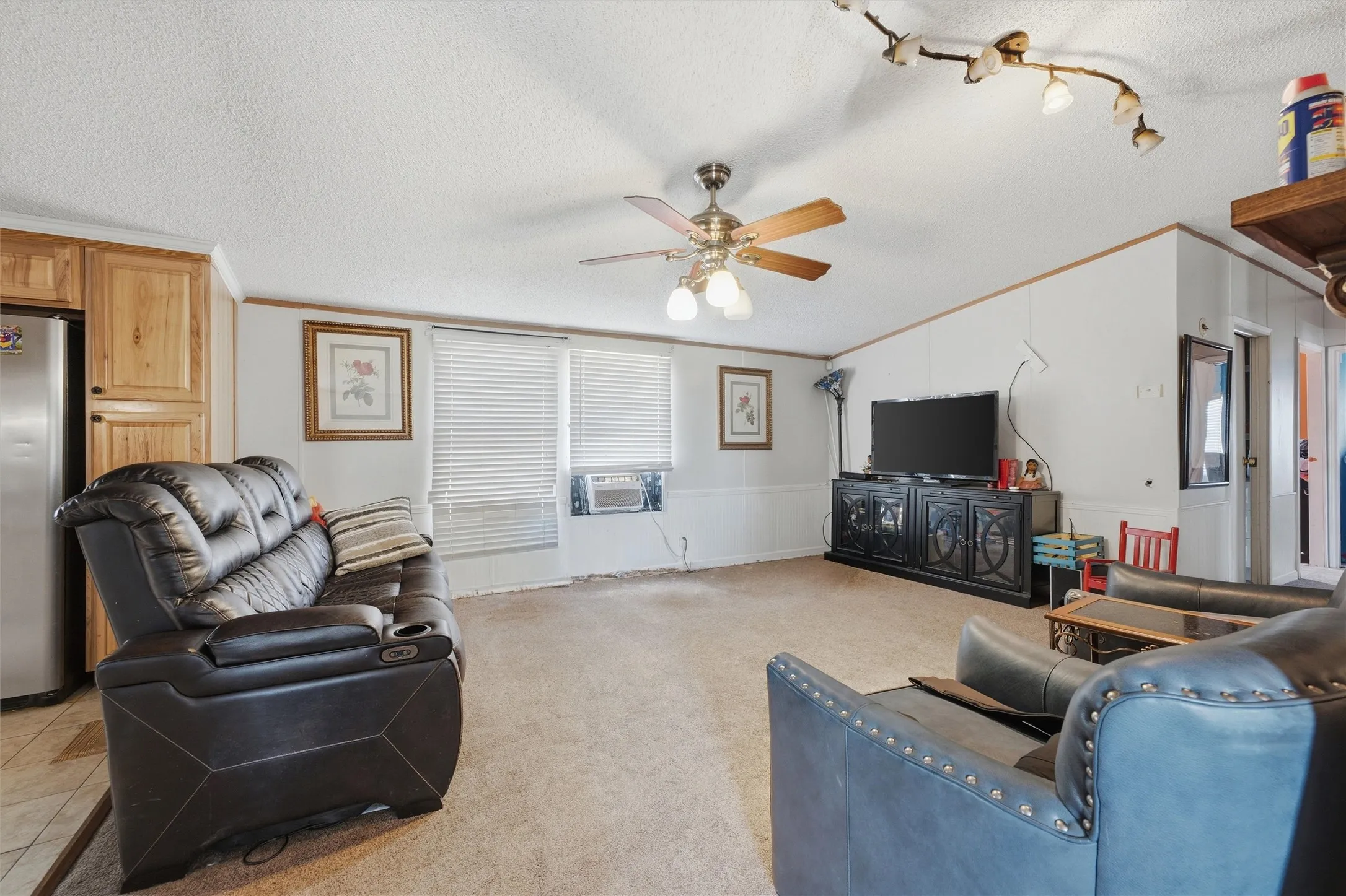 Light-colored carpeting, ceiling fan with integrated lighting, track lighting fixture, and a window with blinds