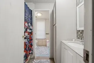 White vanity with integrated sink, white storage cabinetry, and tile backsplash