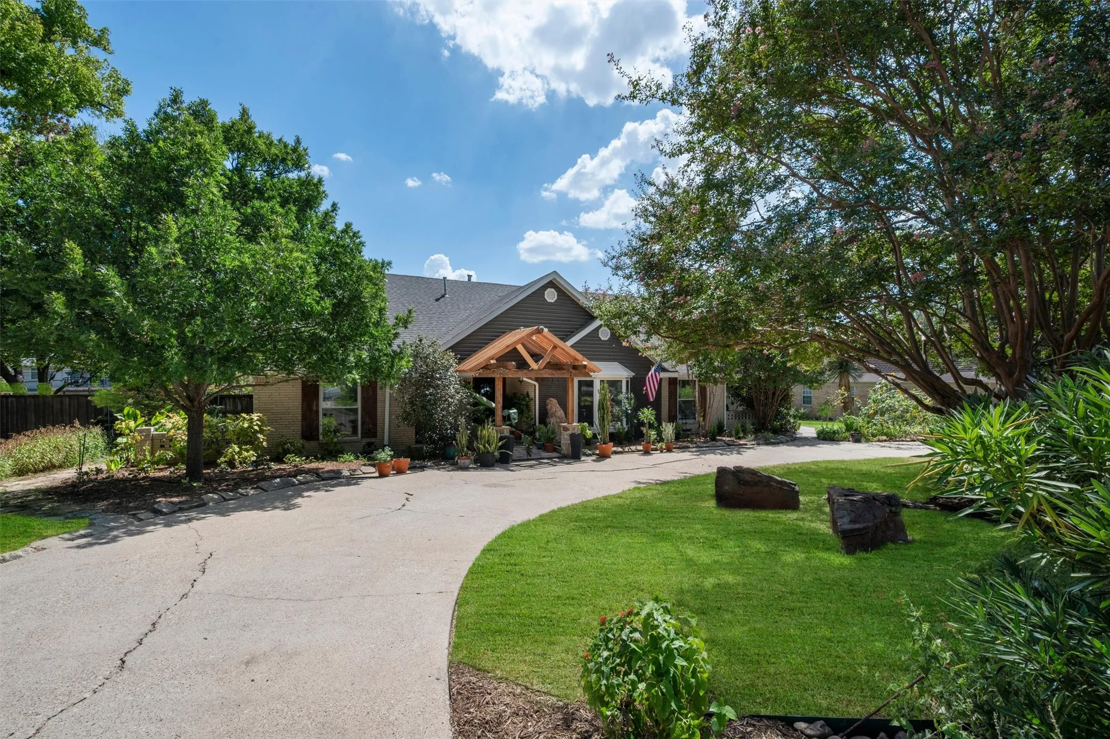 Mature trees, expansive green lawn, and a curved concrete driveway