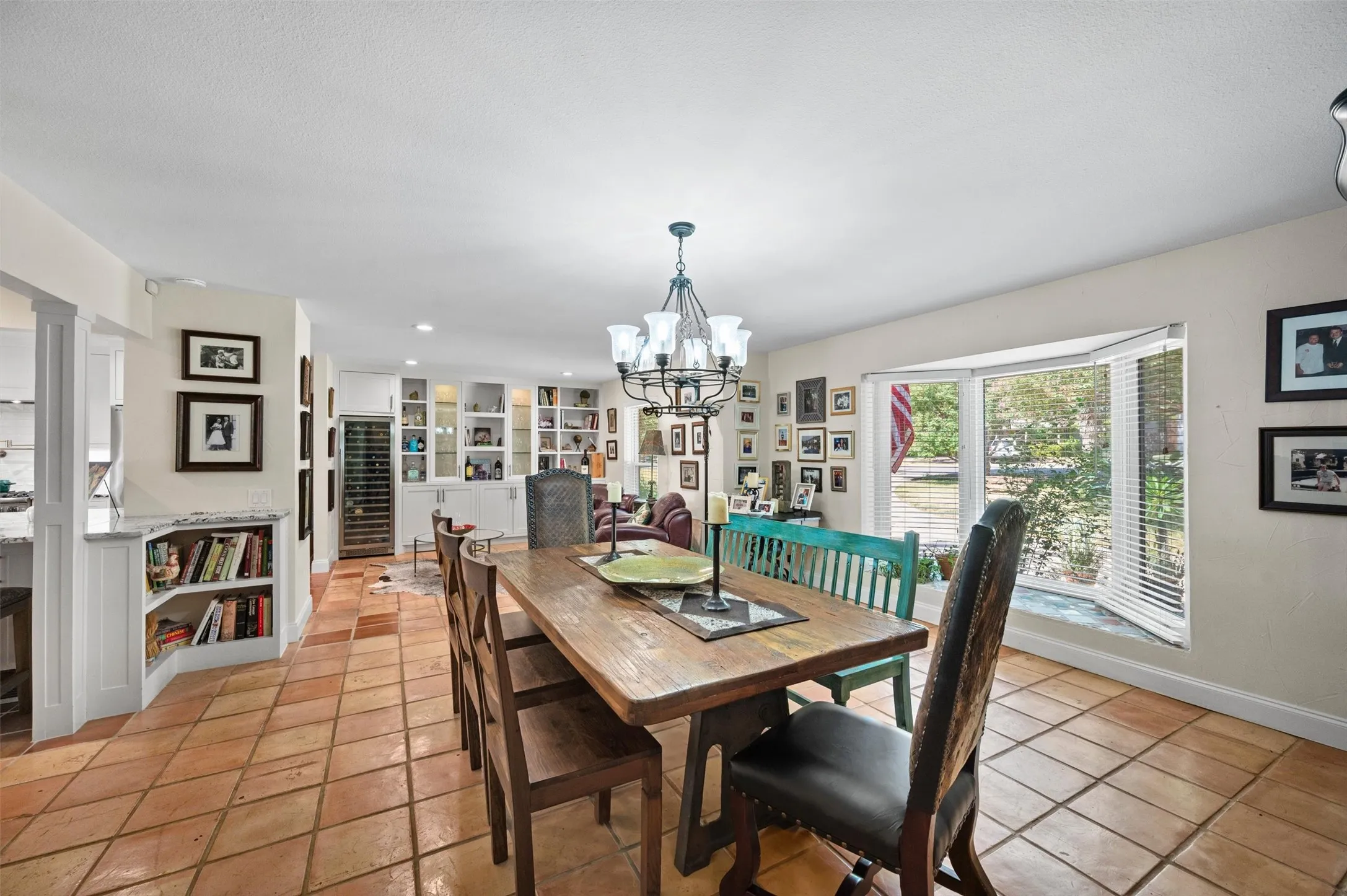 Terracotta tile flooring, built-in shelving, bay window, and a chandelier