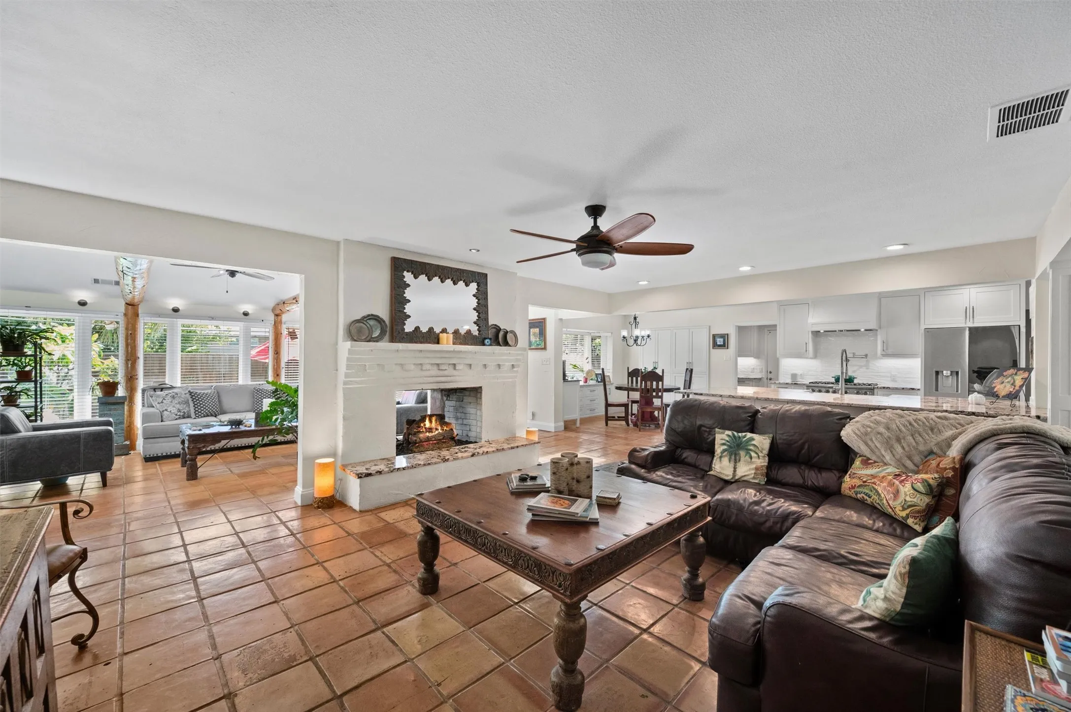Spacious living area featuring terra cotta tile flooring, a white brick fireplace, and recessed lighting