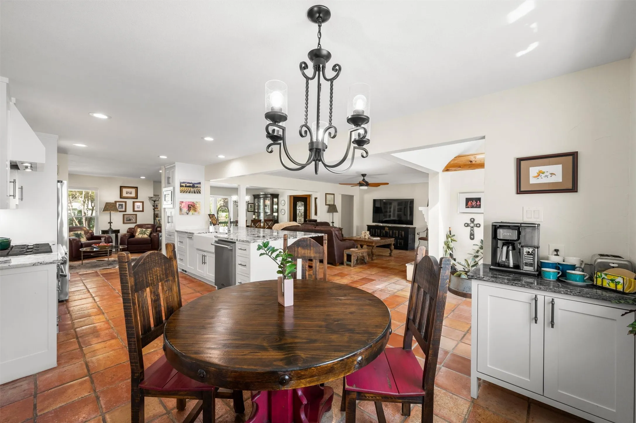 Open-concept living area with terracotta tile flooring, a kitchen island, and a built-in beverage station featuring white cabinetry and a stone countertop