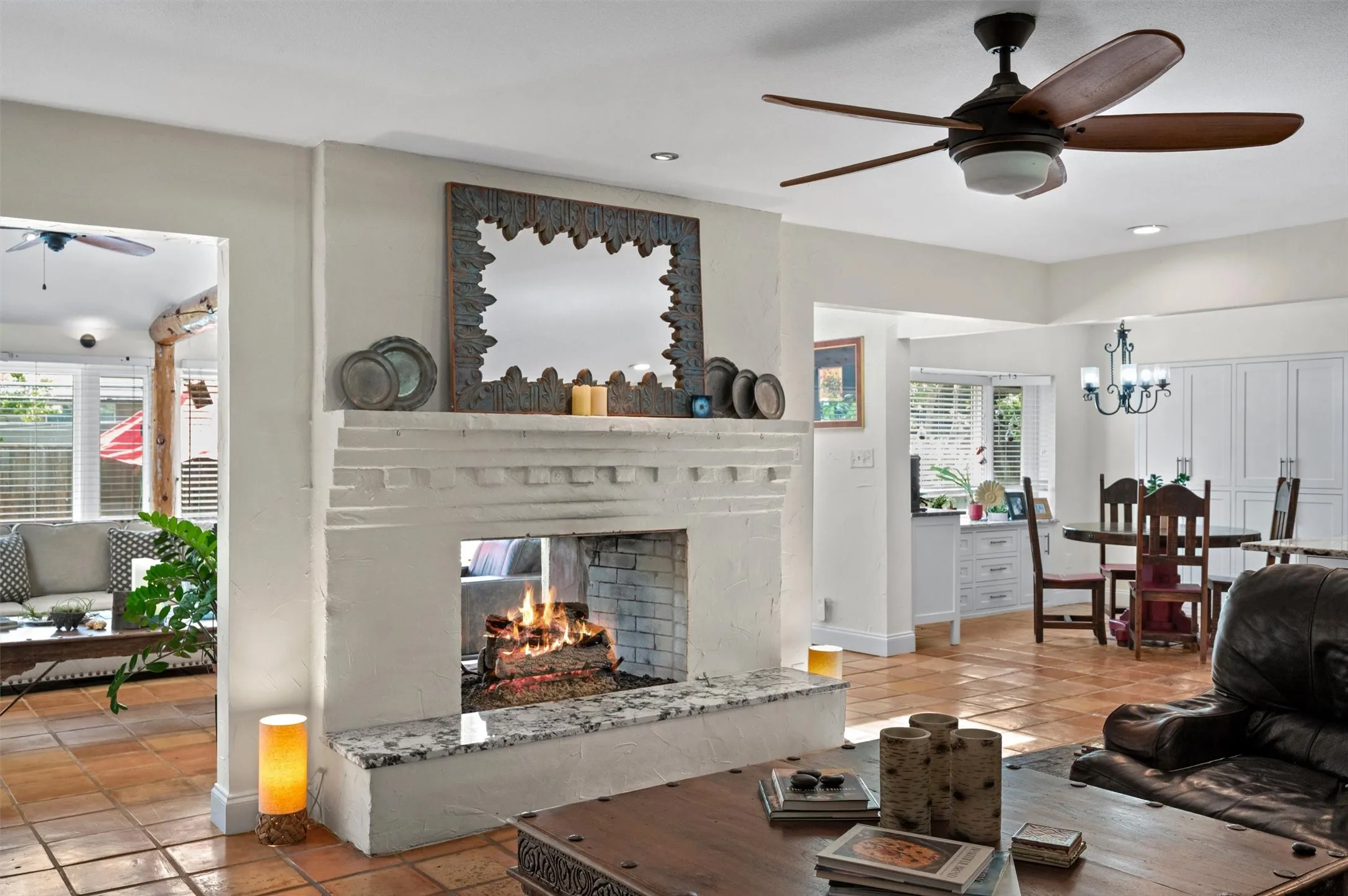 Fireplace with a stone surround and hearth, tiled flooring, ceiling fan with integrated lighting, and an open archway