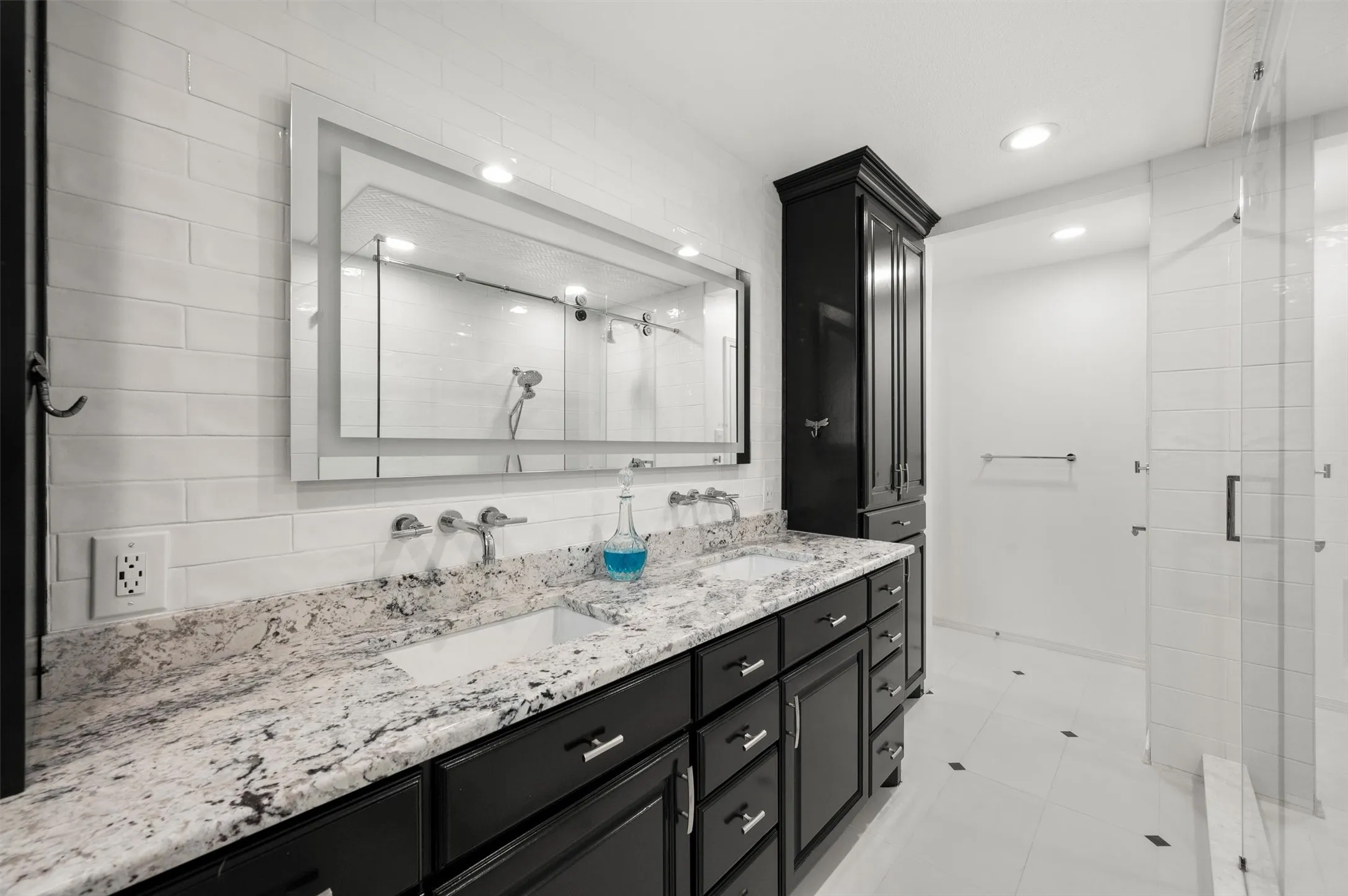 Dual basin vanity with stone countertop, dark wood-finish cabinetry, and framed mirror