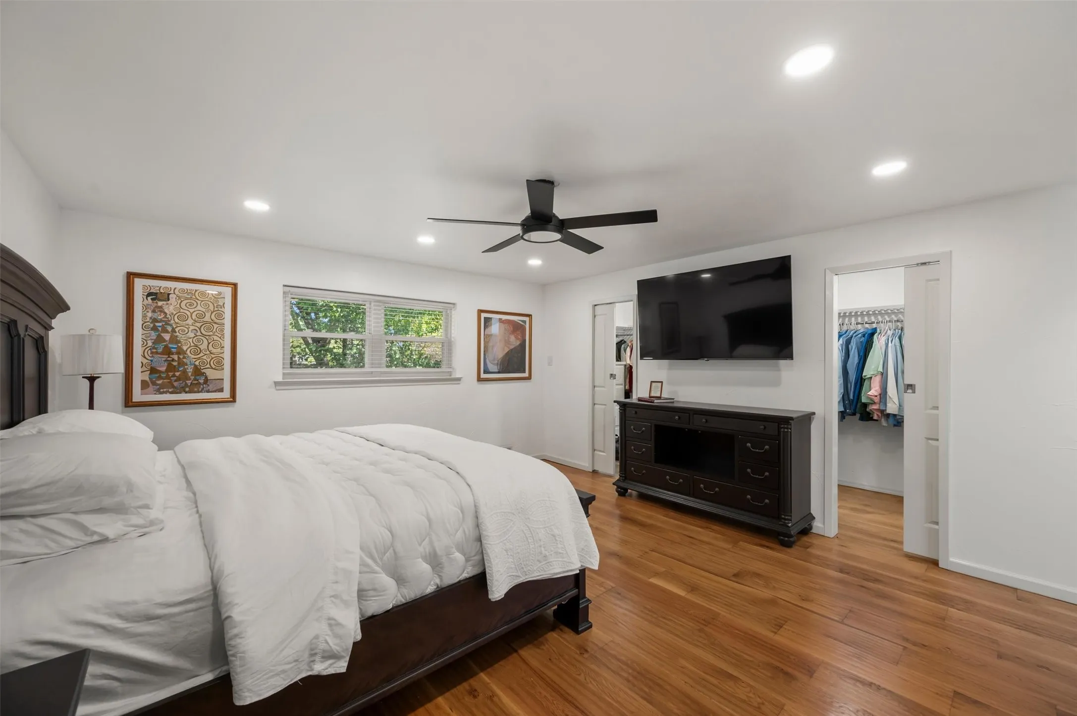 Wood-finish flooring with recessed lighting, ceiling fan, and built-in closet