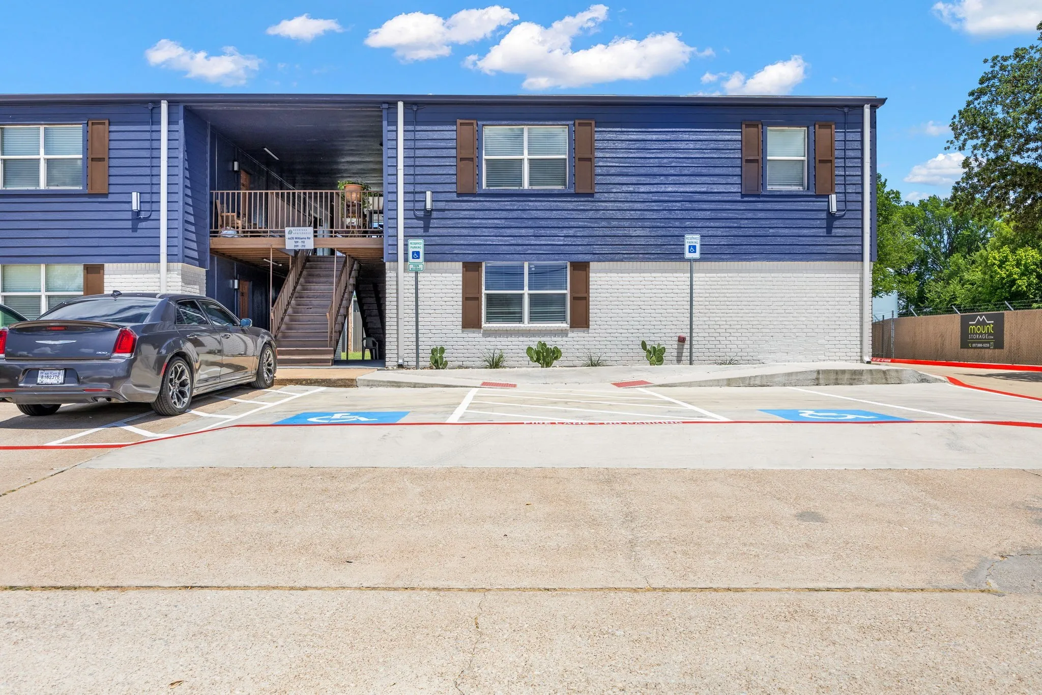 View of property with uncovered parking and stairs