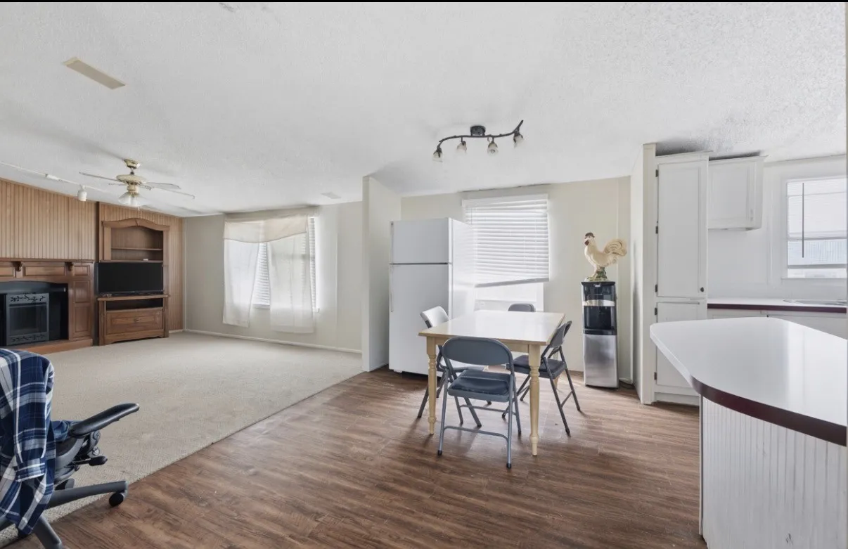 Open-concept living area featuring wood-finish flooring, a built-in media center with a fireplace, and a ceiling fan