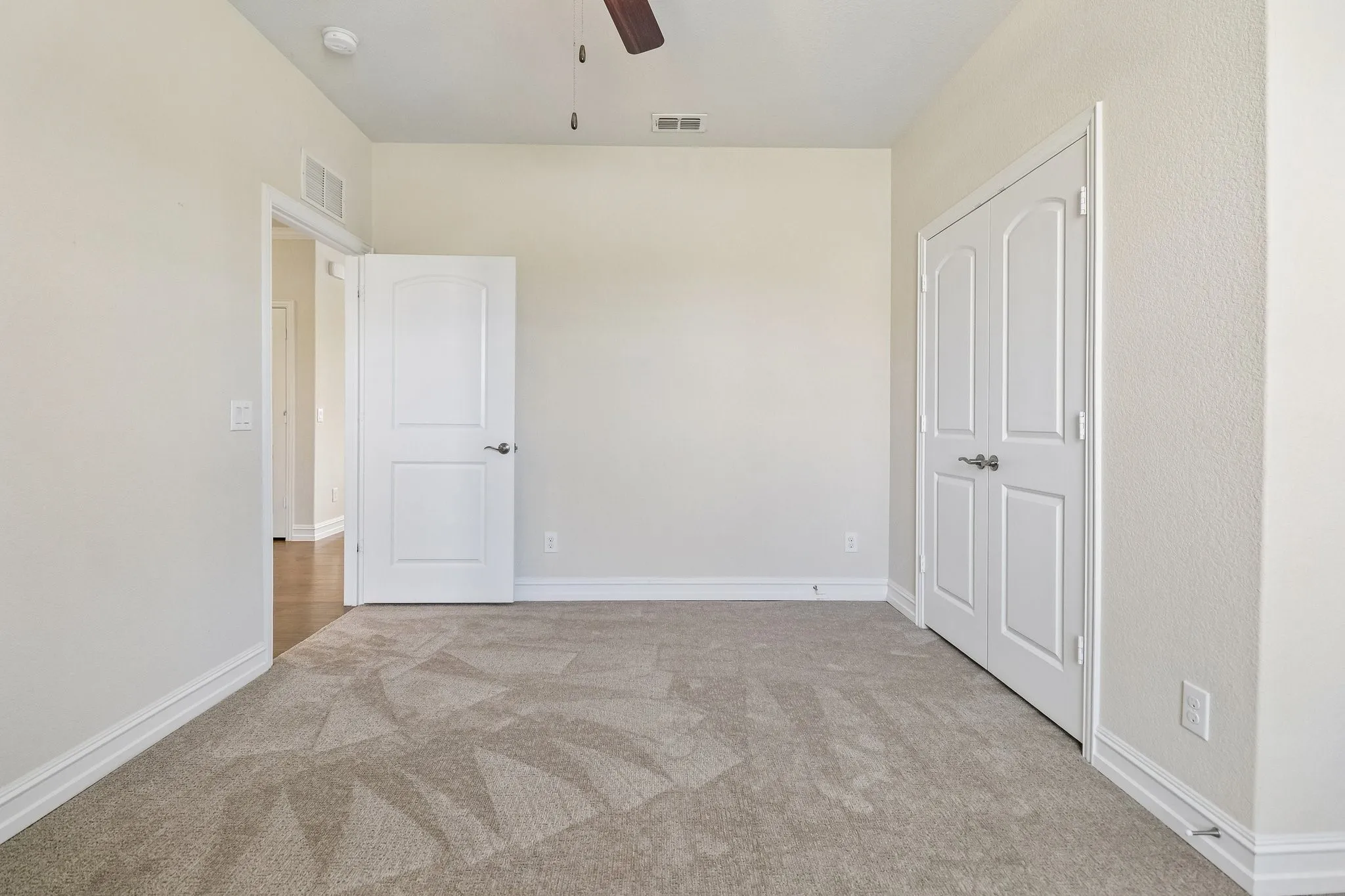 Neutral wall color, patterned carpet flooring, ceiling fan, and white paneled doors