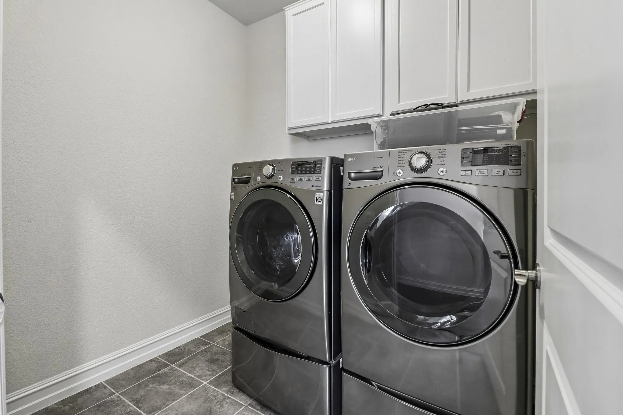 Upper cabinetry with shaker-style doors, durable tile flooring, and light-toned walls
