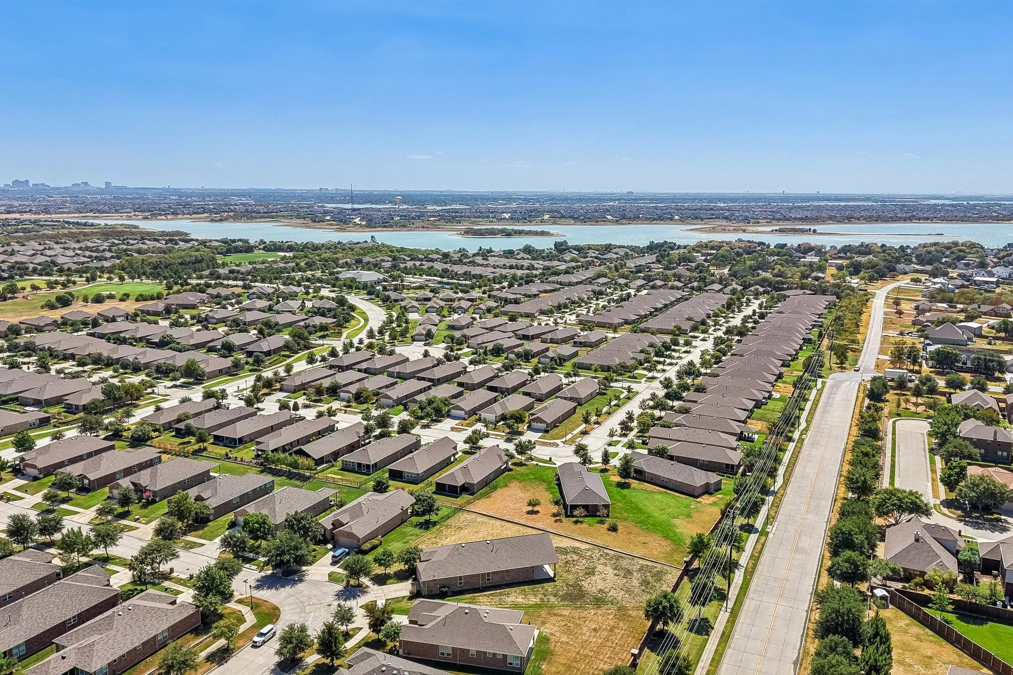 Expansive neighborhood with numerous single-story properties and mature landscaping, situated near a substantial body of water