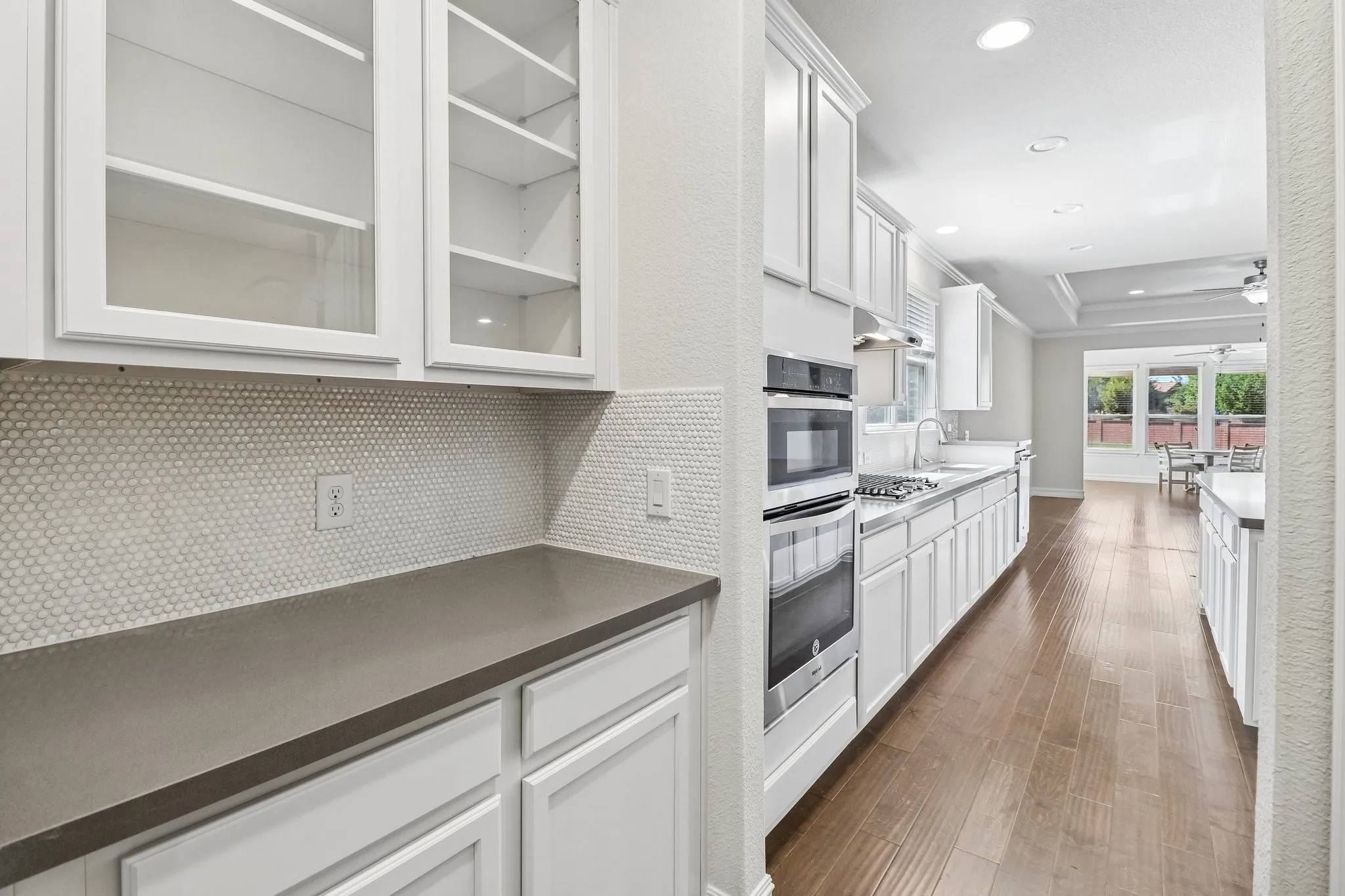 Kitchen featuring white cabinetry, dark countertops, a penny tile backsplash, and wood-finish flooring