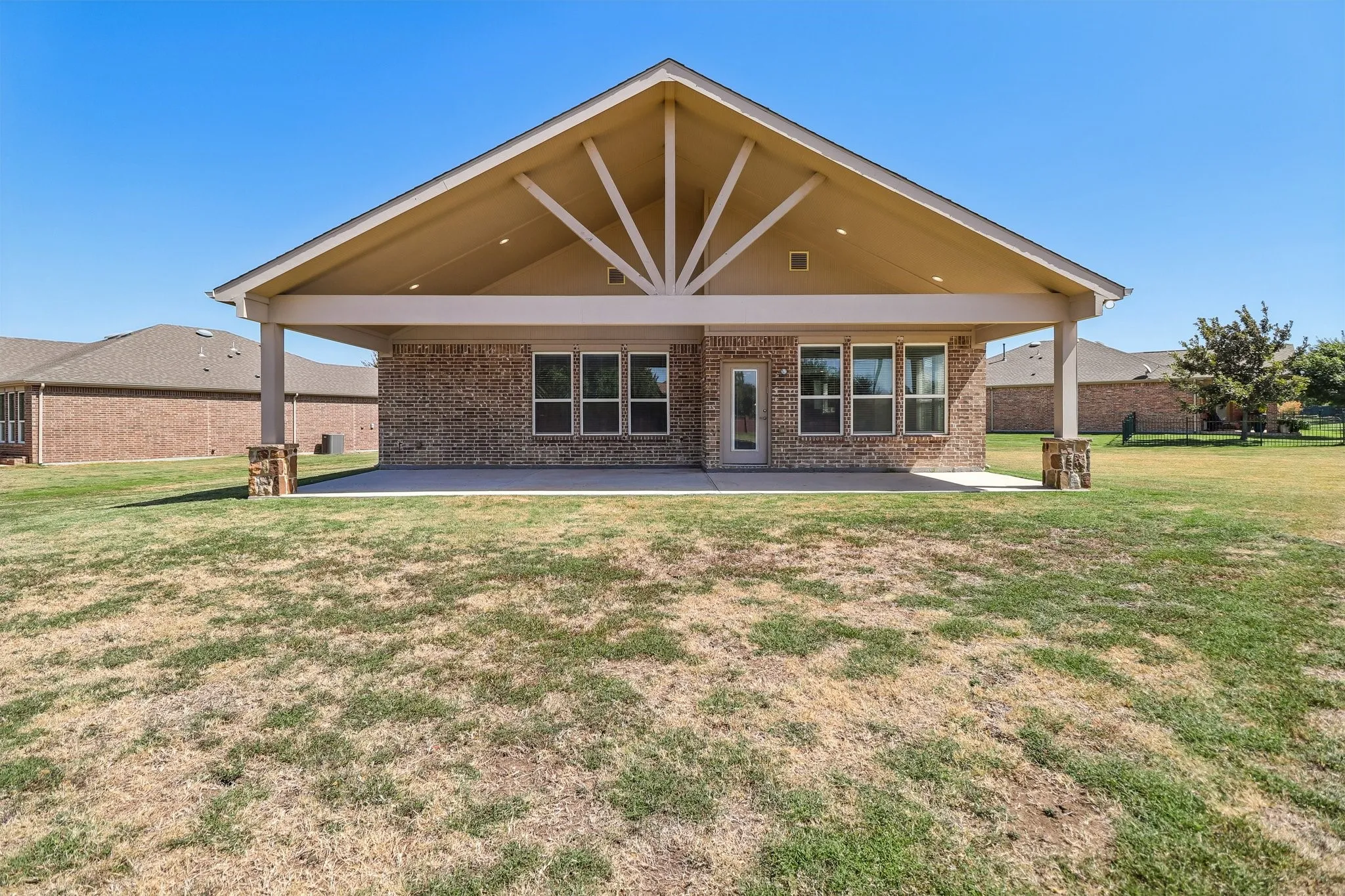 Expansive covered patio featuring a vaulted ceiling and exposed rafter tails