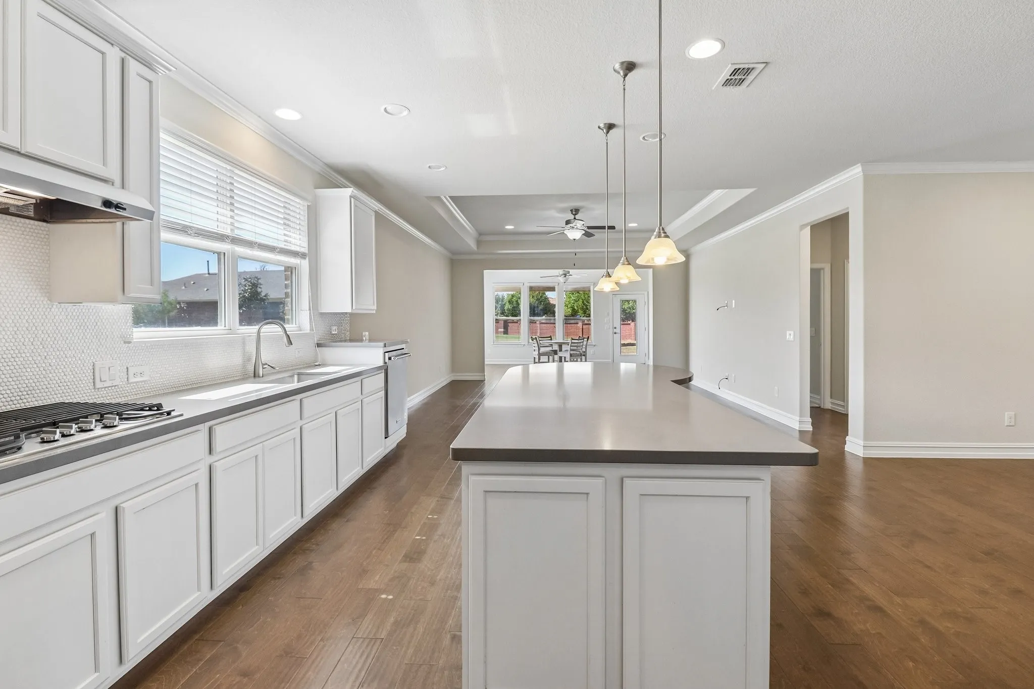 Kitchen featuring white shaker cabinetry, stainless steel appliances, a tile backsplash, and a central island with pendant lighting