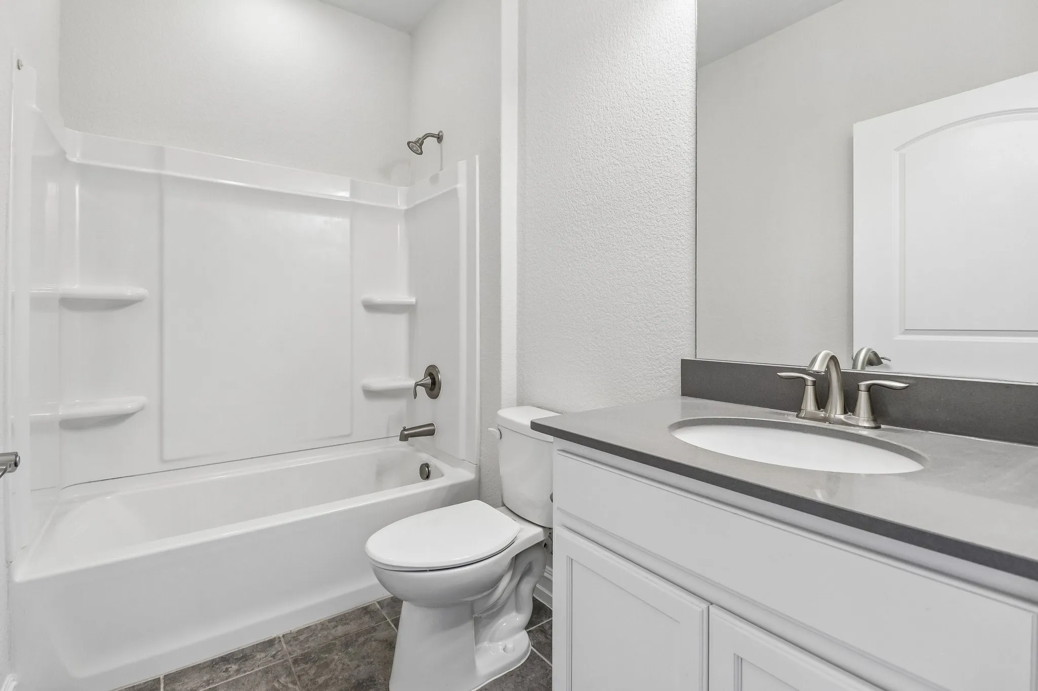 White vanity with a built-in sink and a gray countertop, complete with a chrome faucet