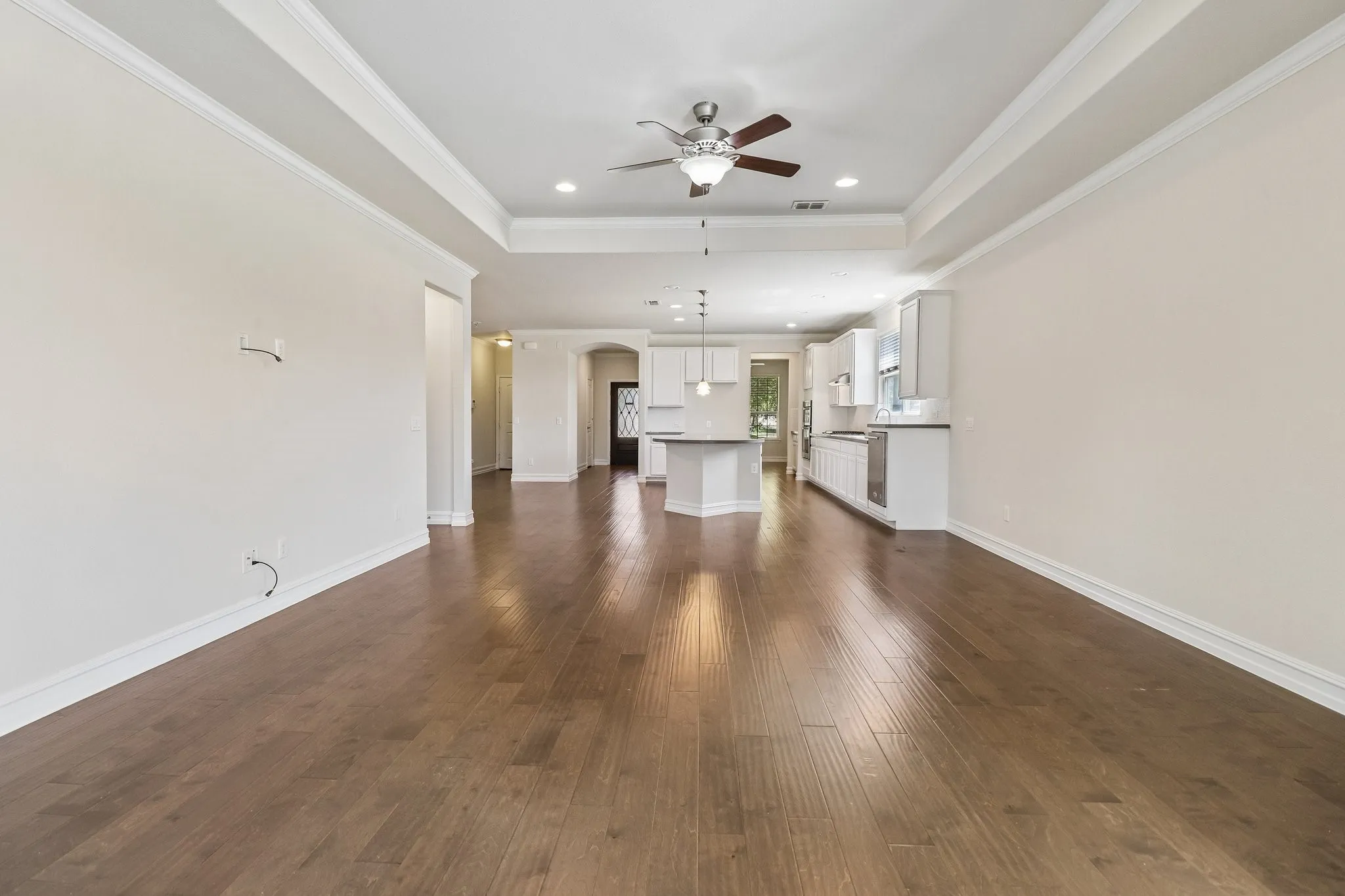 Hardwood-finish flooring, recessed lighting, ceiling fan, tray ceiling, and white crown molding