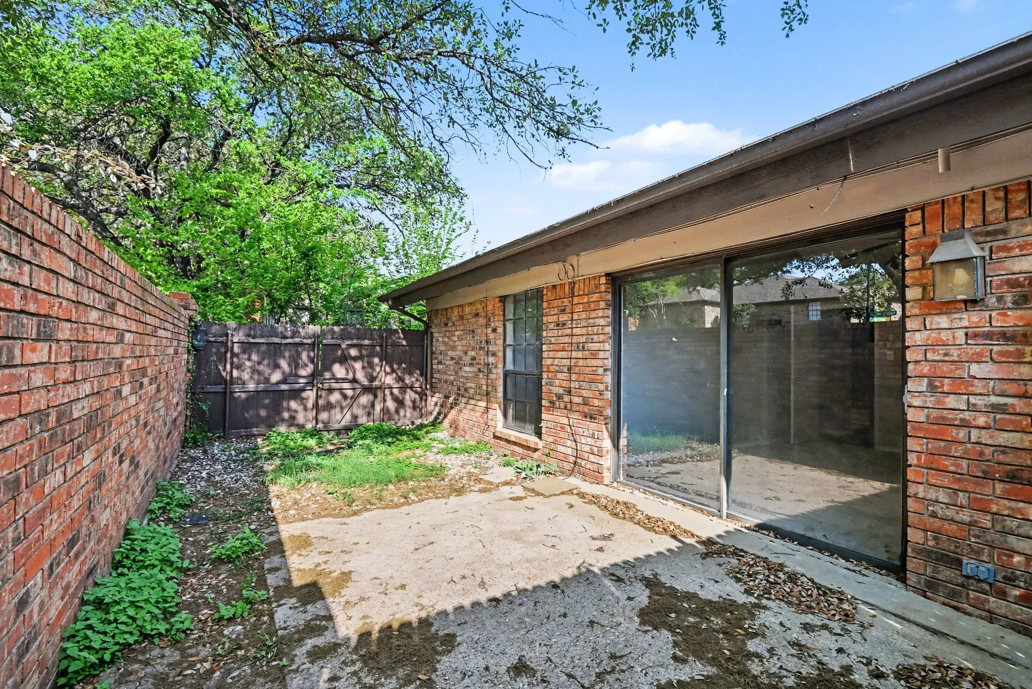 Brick exterior with sliding glass door and wall-mounted exterior light fixture