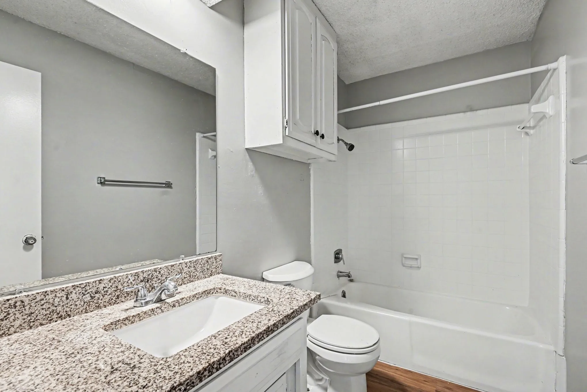 Bathroom featuring a vanity with a granite-style countertop, an undermount sink, and a framed mirror
