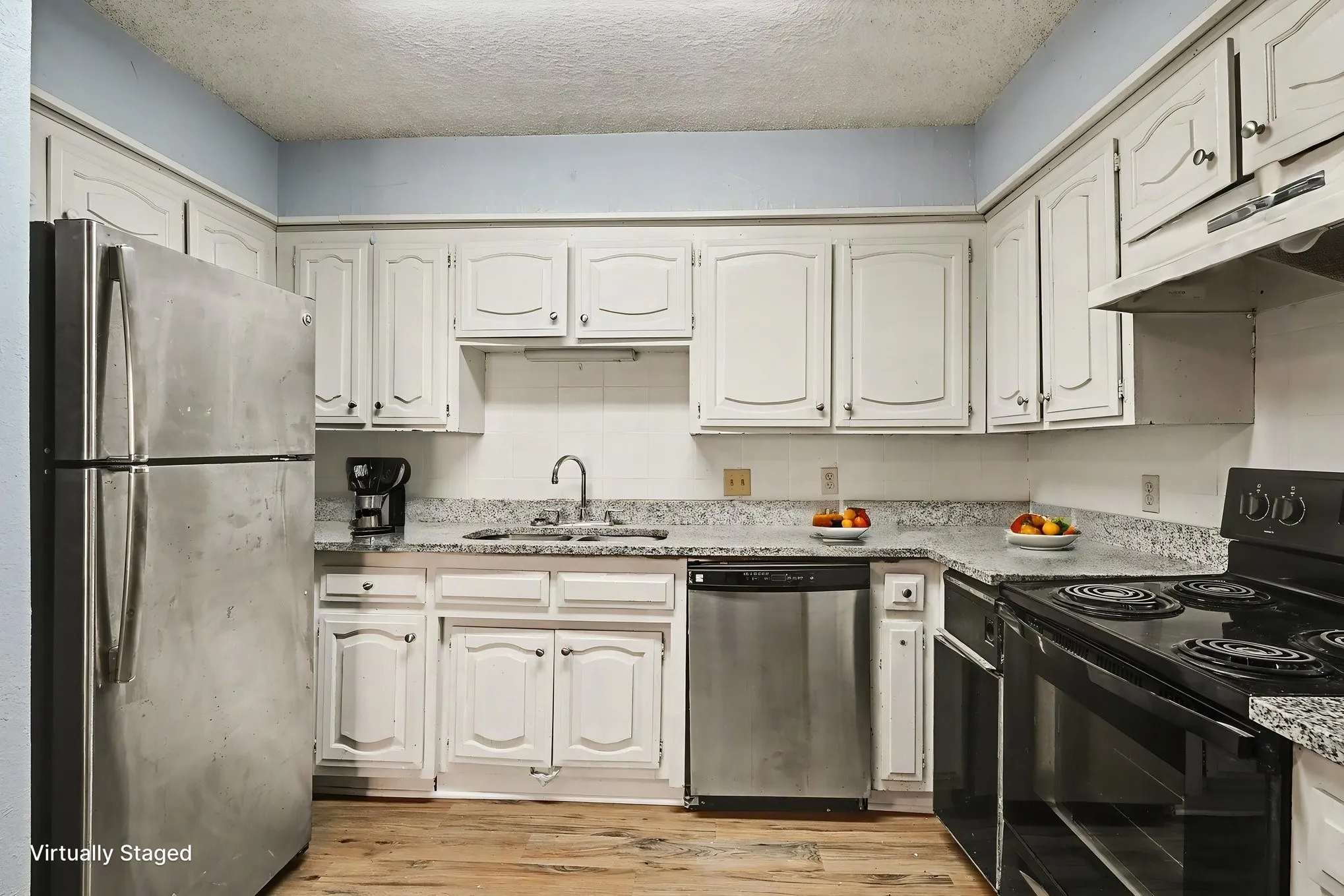 Kitchen featuring white cabinetry, light-toned countertops, wood-finish flooring, and stainless steel appliances