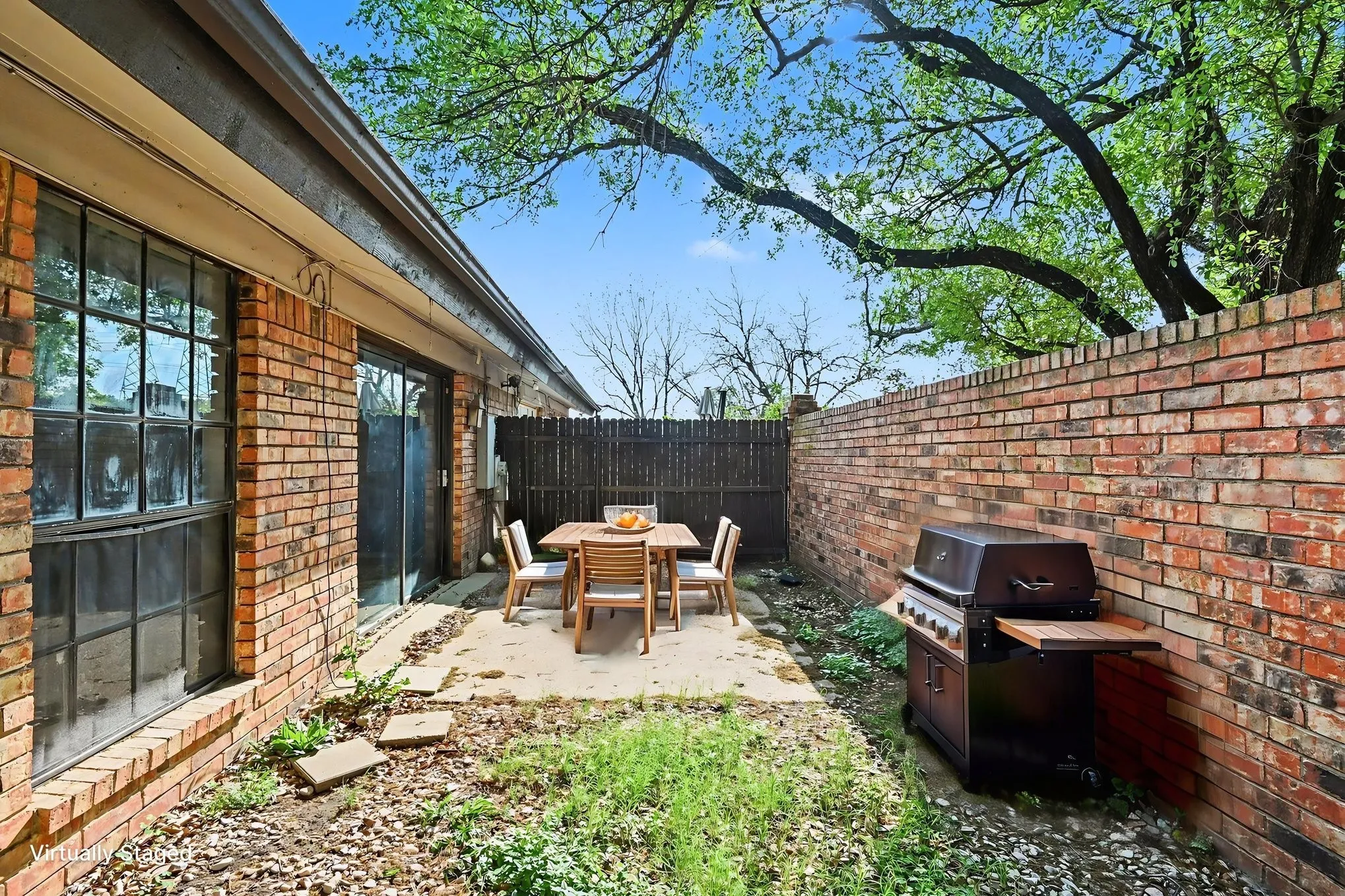 Private outdoor patio with brick wall surround, mature trees, and sliding glass door access