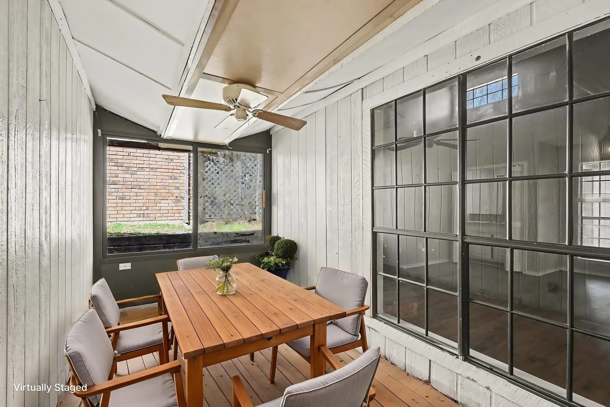 Enclosed patio area featuring a sloped ceiling, paneled walls, and a ceiling fan